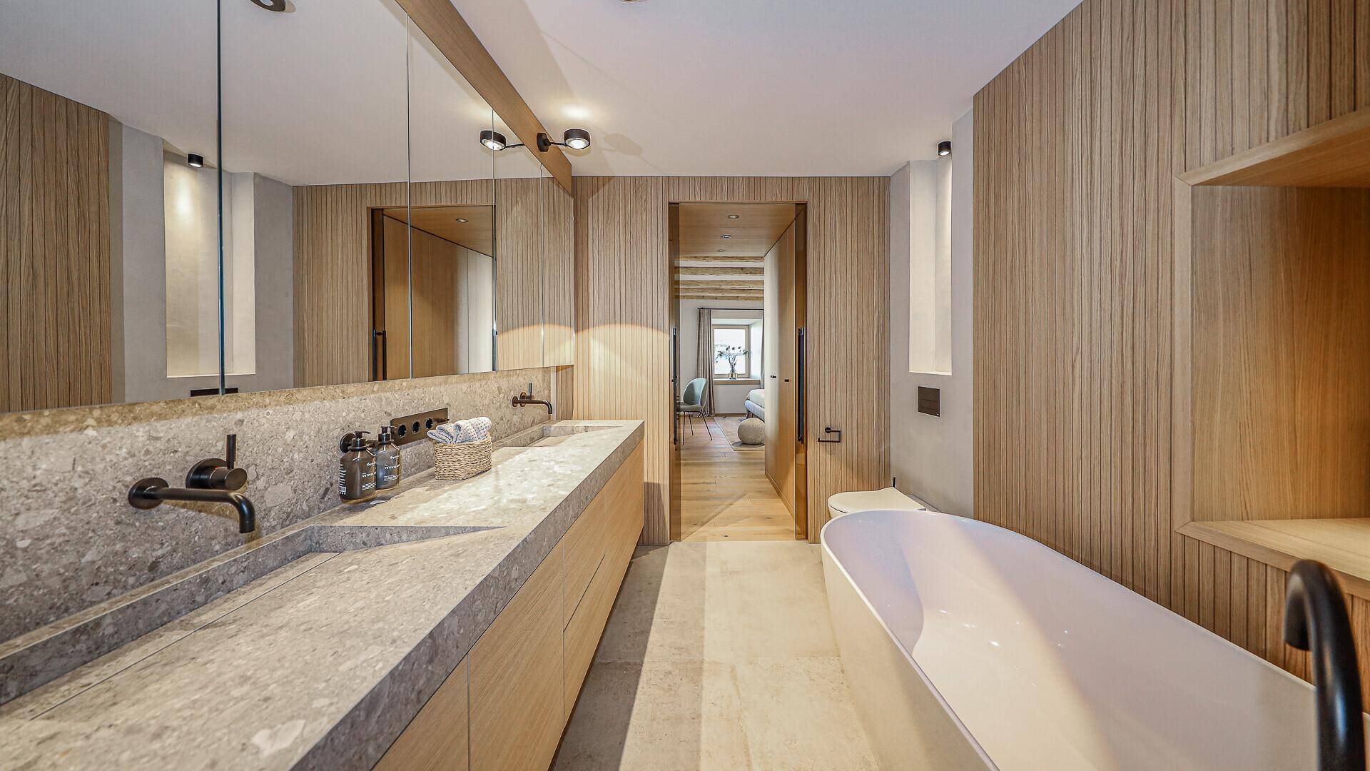 Elegantes Badezimmer mit Doppelwaschbecken, freistehender Badewanne und Holzdetails.