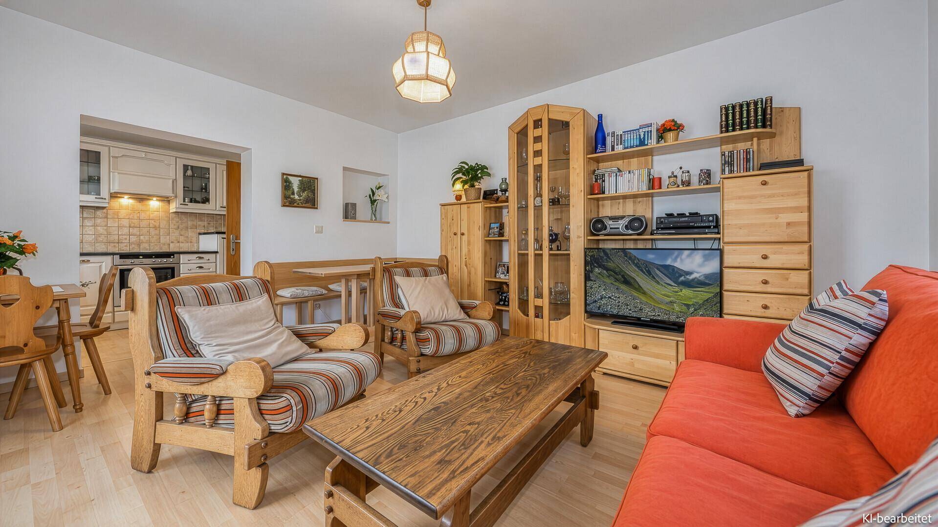 Traditioneller Wohnbereich mit Holzmöbeln, rotem Sofa und Blick auf den Essbereich und die Küche.