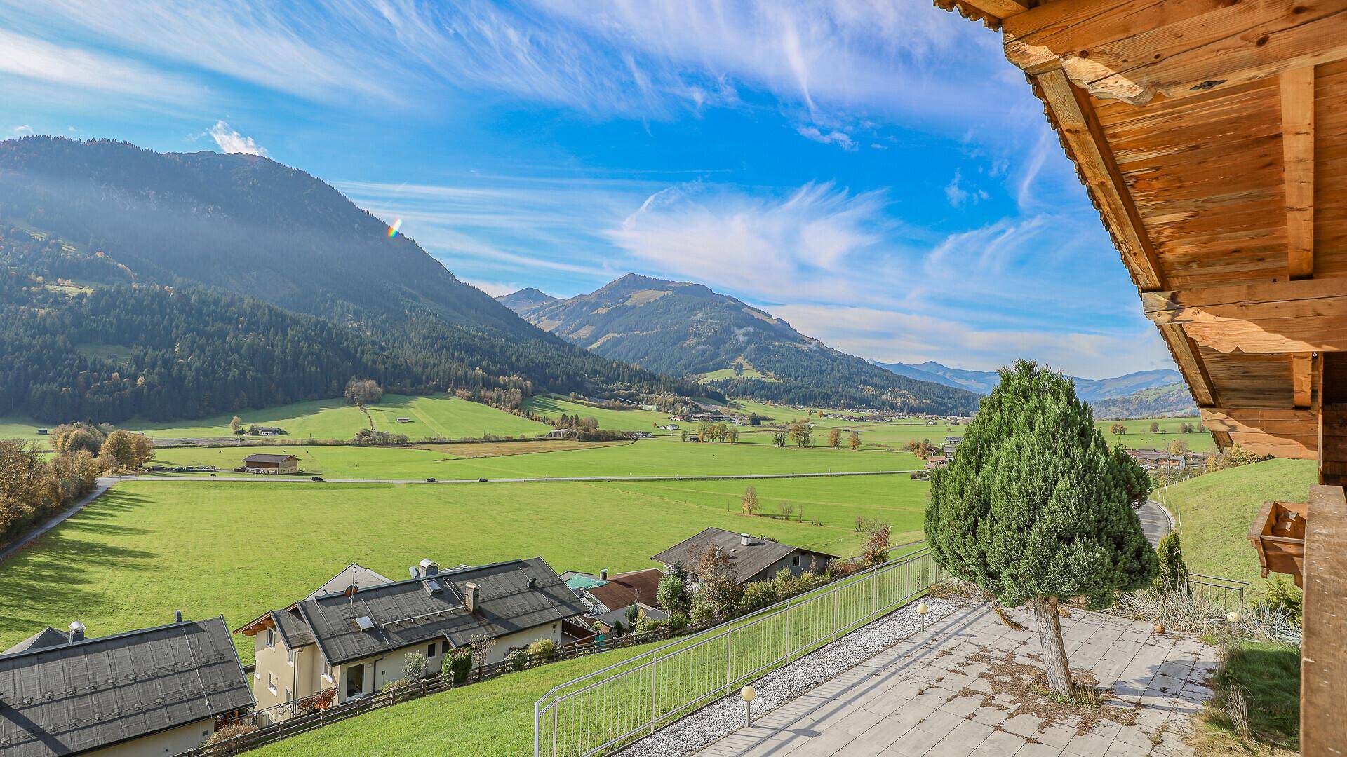 Panoramablick von der Terrasse auf die weiten grünen Felder und die umliegenden Berge.