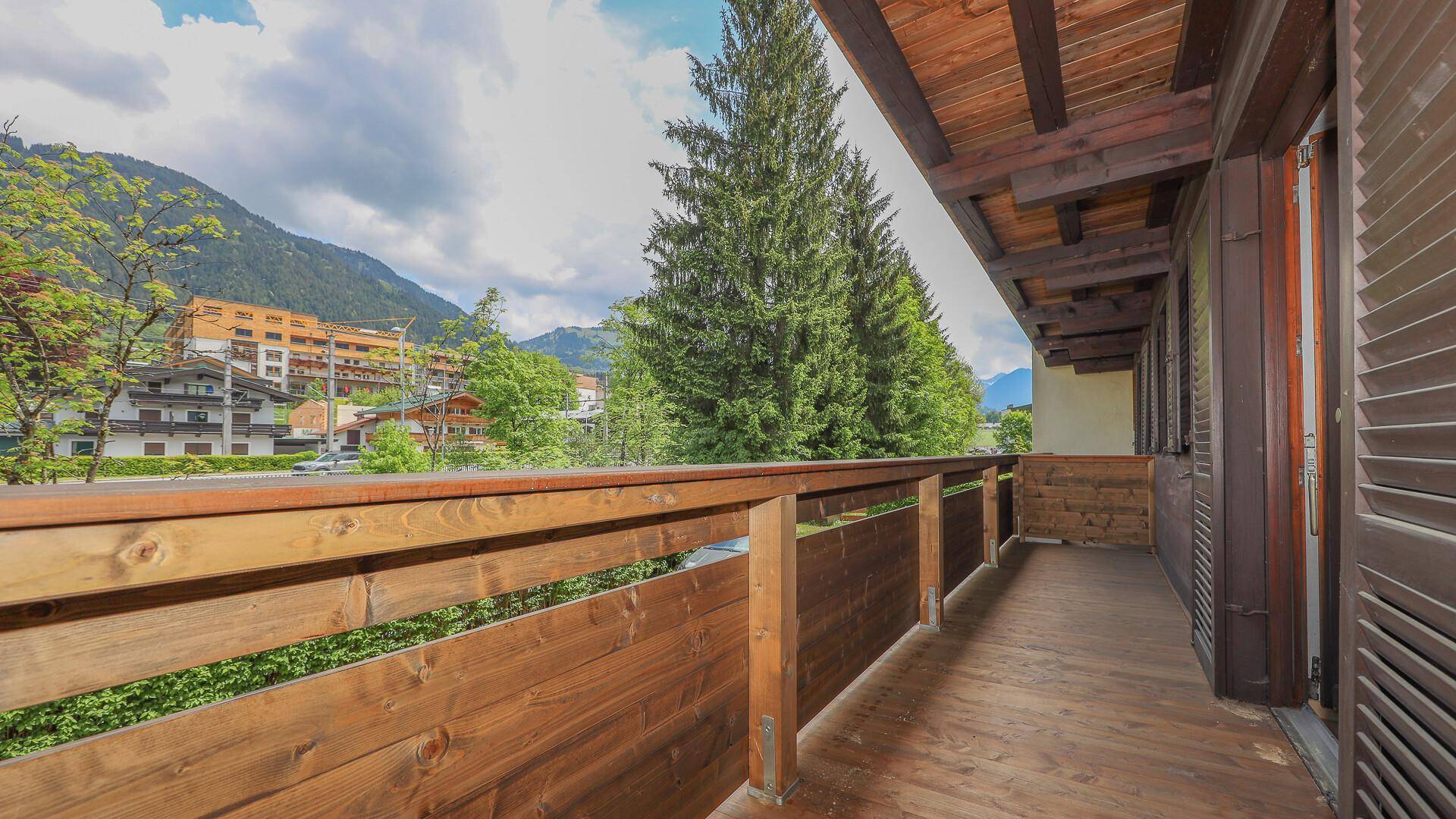 Geräumiger Holzbalkon mit Bergblick und viel Grün in der Umgebung.