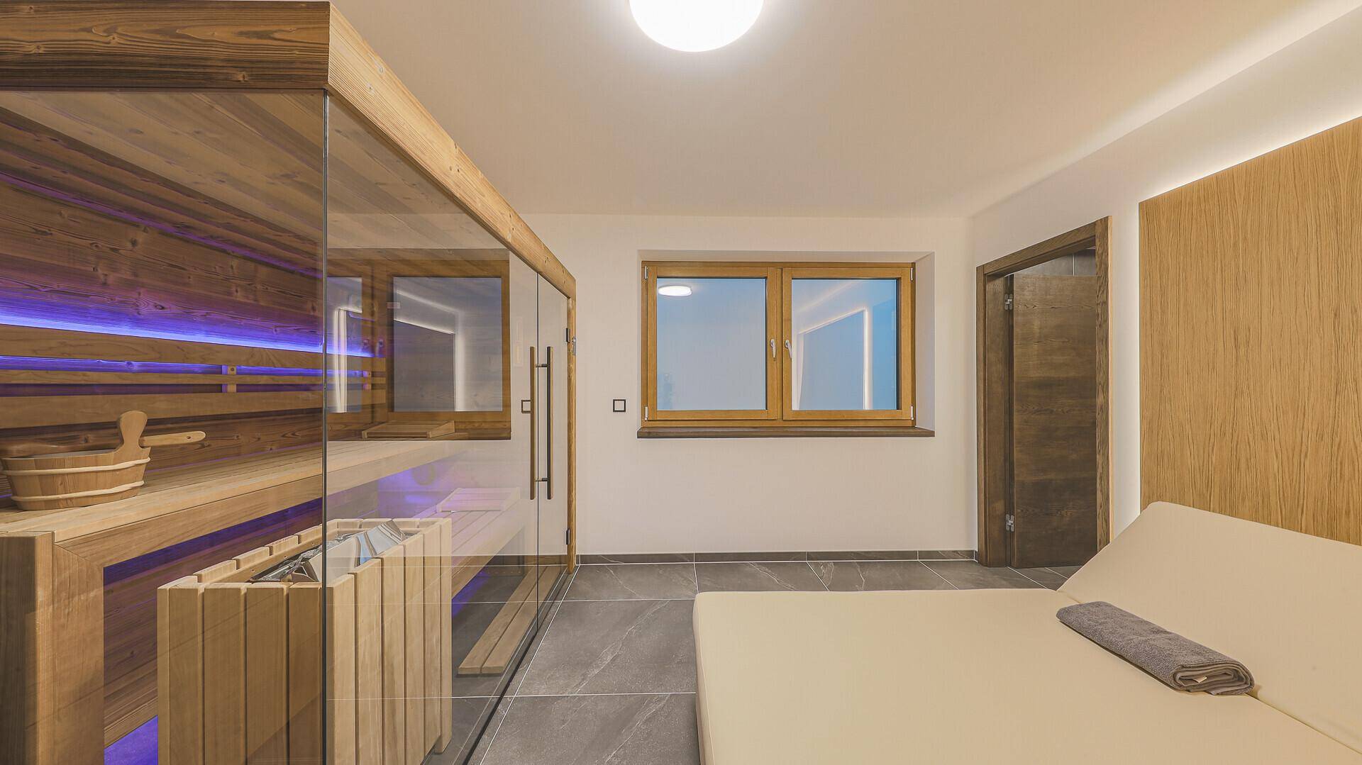 Wellnessbereich mit moderner Sauna, Liegefläche und Fenster für eine helle Atmosphäre.