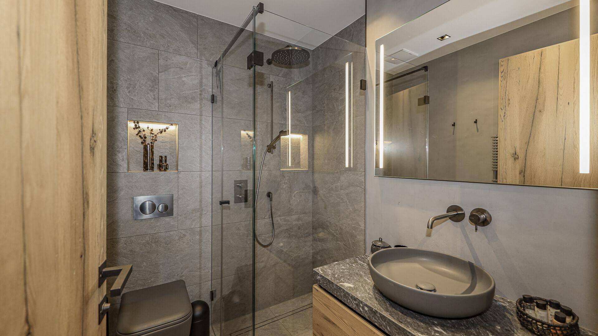 Kompaktes Badezimmer mit Einzelwaschbecken, begehbarer Dusche und wandhängendem WC.