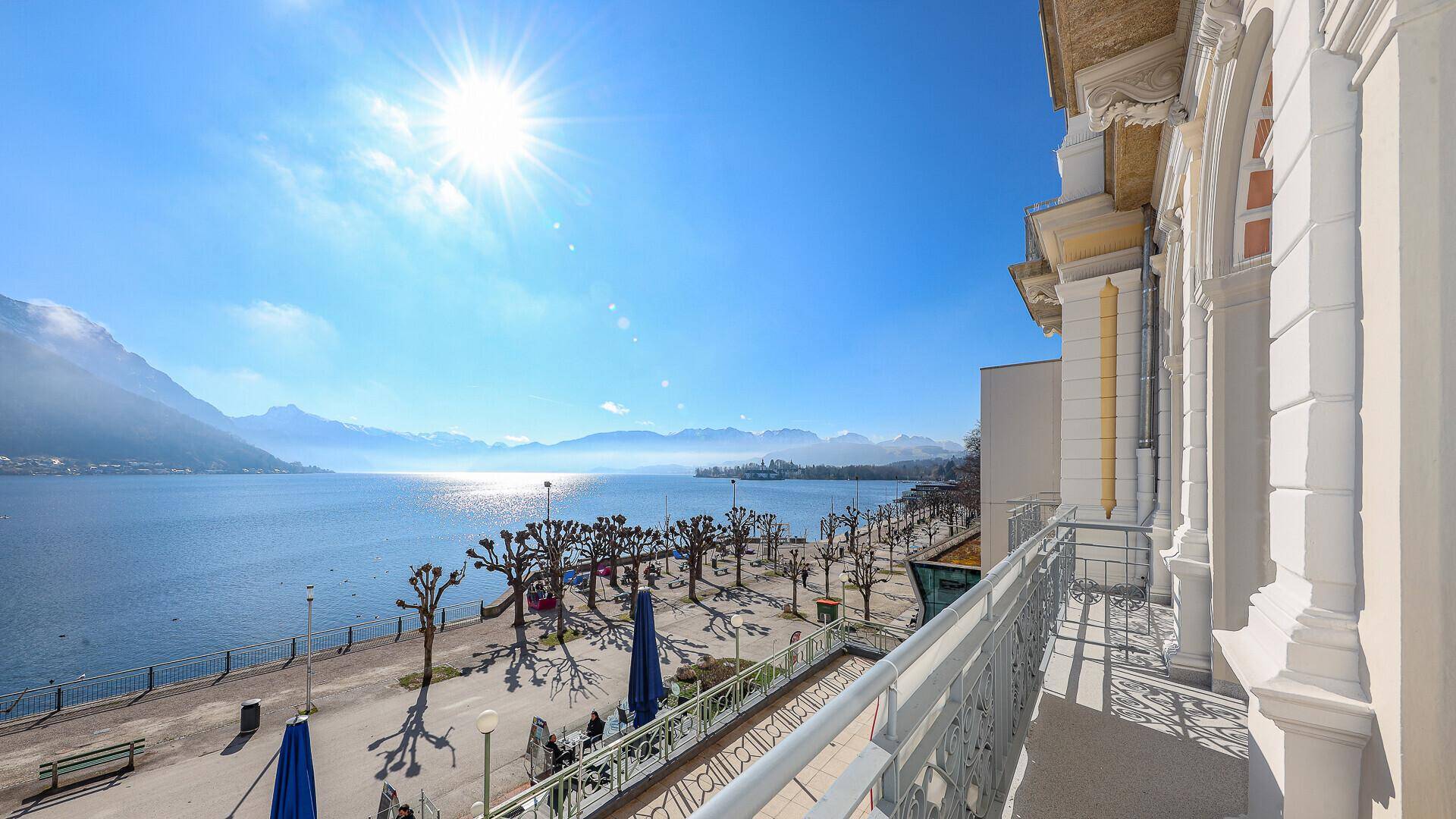Balkon mit seitlichem Blick auf die historische Fassade, den See und die belebte Promenade.