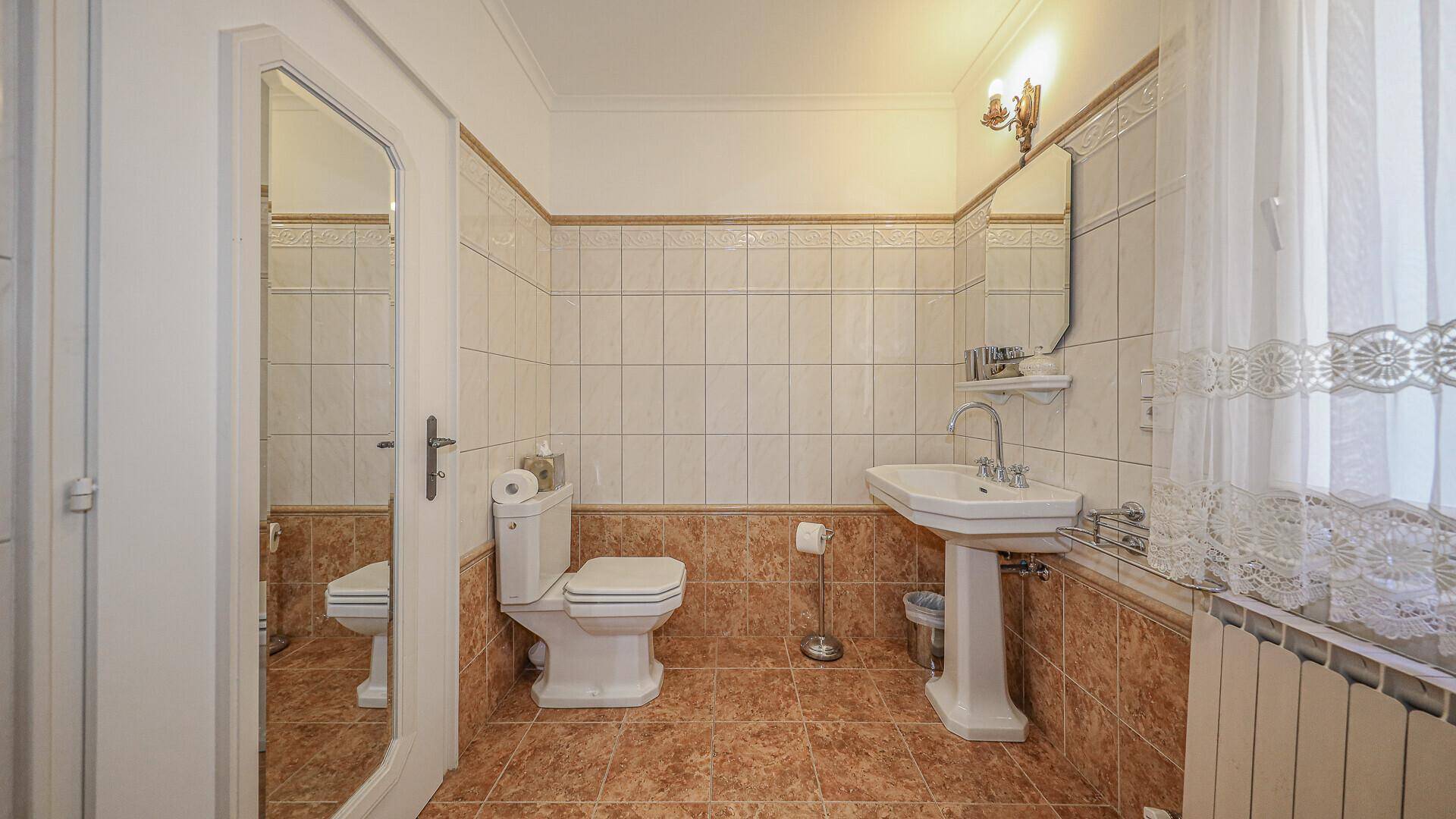 Kleines Badezimmer mit Fliesenboden, Standwaschbecken und WC, in traditionellem Stil.