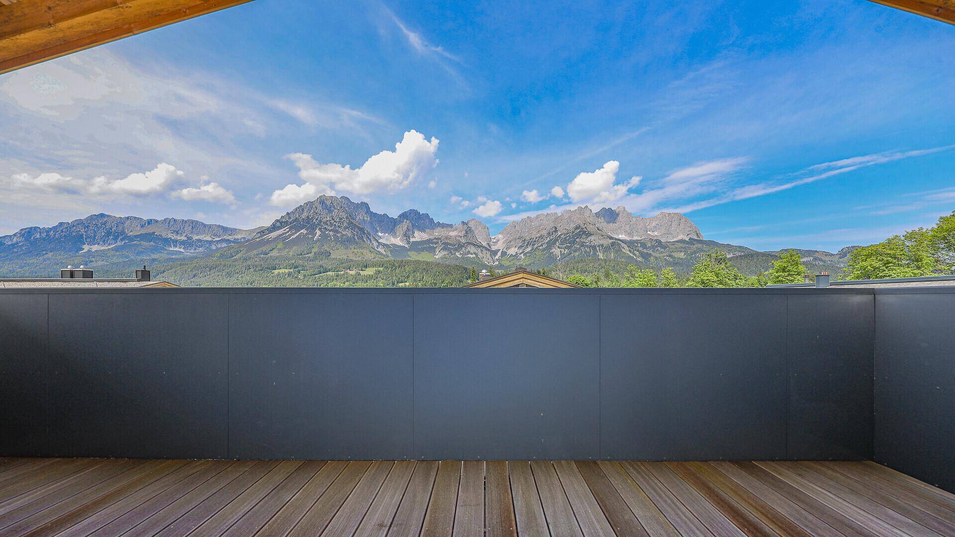 Geräumiger Balkon mit Holzboden und weitem Blick auf die umliegende Berglandschaft.