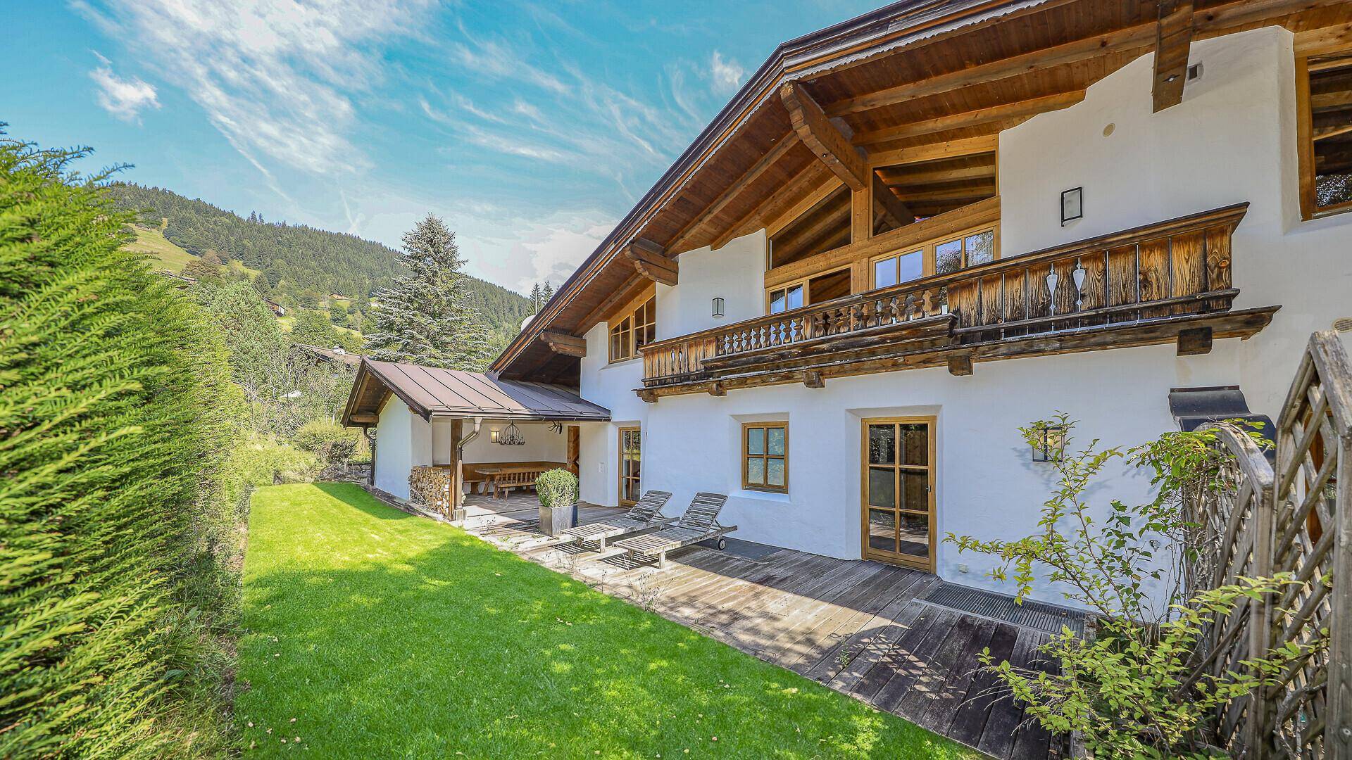 Gepflegter Gartenbereich mit Rasenfläche und Holzterrasse am Haus.