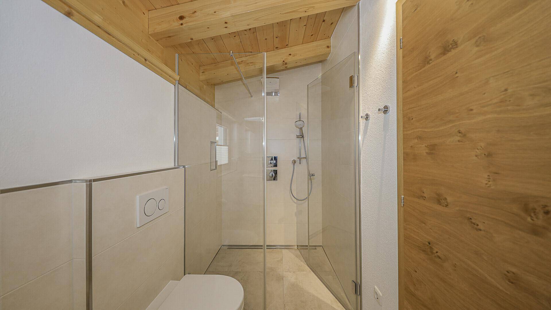 Modernes Badezimmer mit begehbarer Dusche und Wand-WC unter der Dachschräge.