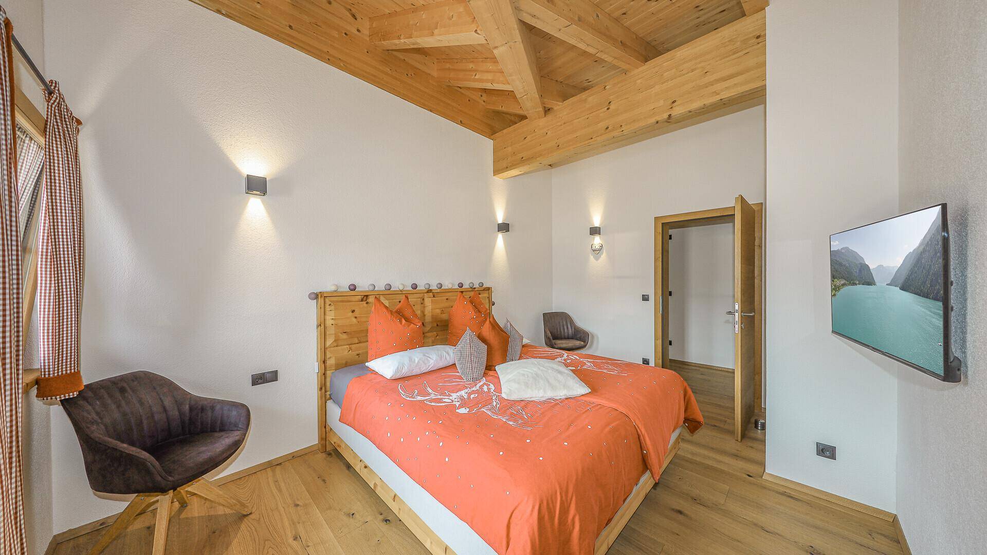 Geräumiges Schlafzimmer mit hoher Holzdecke, Doppelbett und moderner Einrichtung.