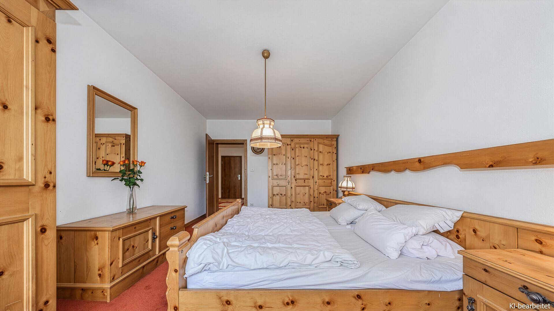 Gemütliches Schlafzimmer mit traditionellen Holzmöbeln und rotem Teppichboden.