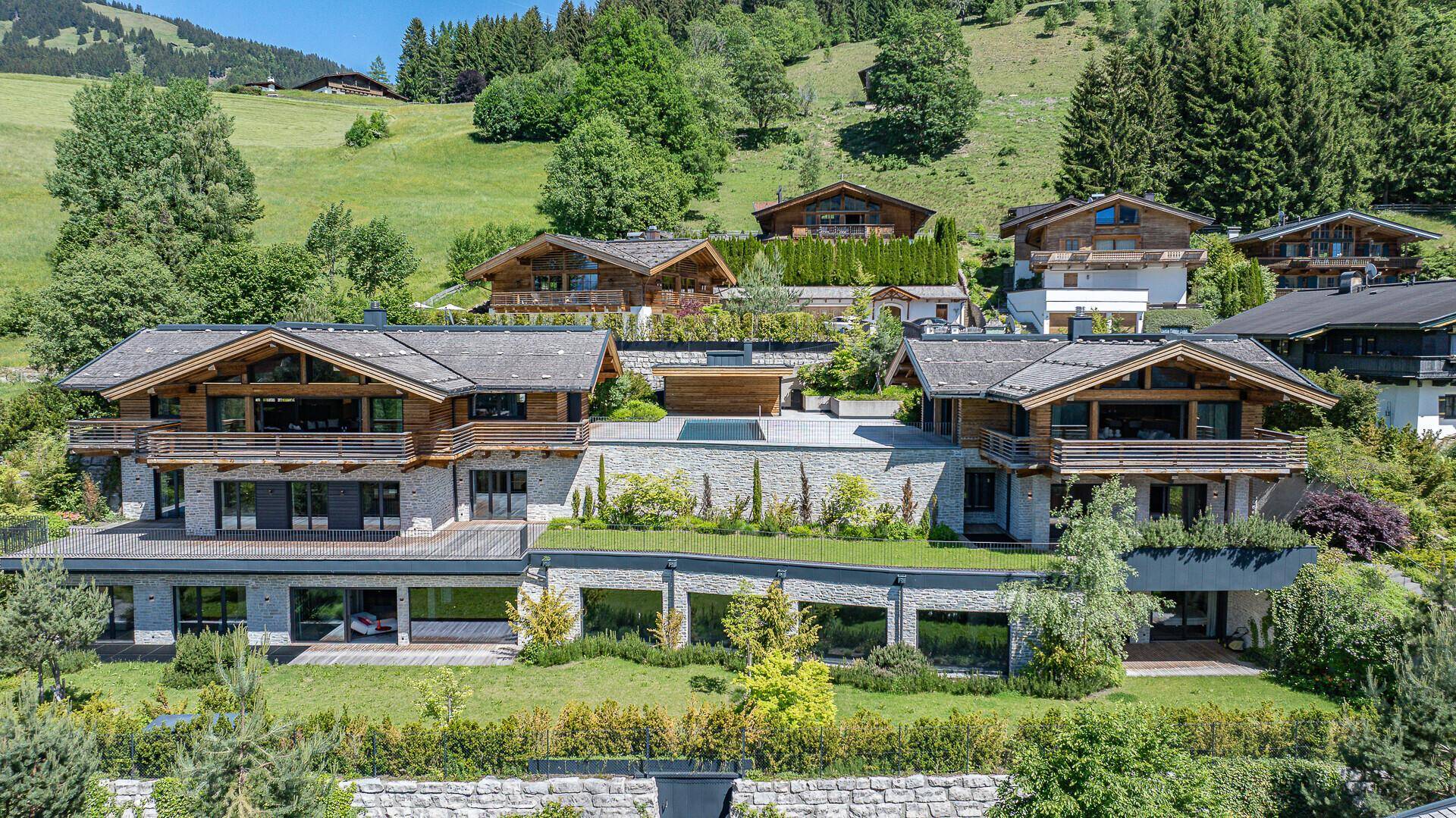 Exklusive Chalet-Anlage mit Infinity-Pool und weitläufiger Terrasse in idyllischer Berglandschaft.