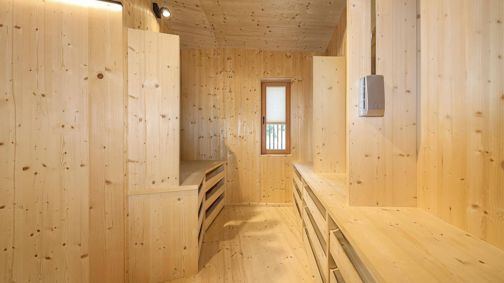 Geräumiger begehbarer Kleiderschrank mit maßgefertigten Holzregalen und einem Fenster.