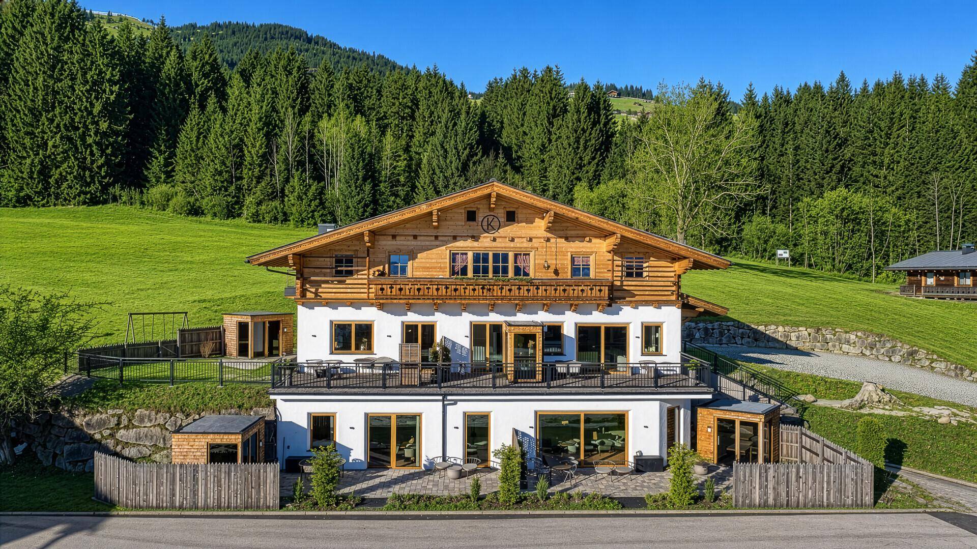 Traditionelles Chalet mit moderner Architektur, Holzbalkonen und Blick auf die umliegende Natur.