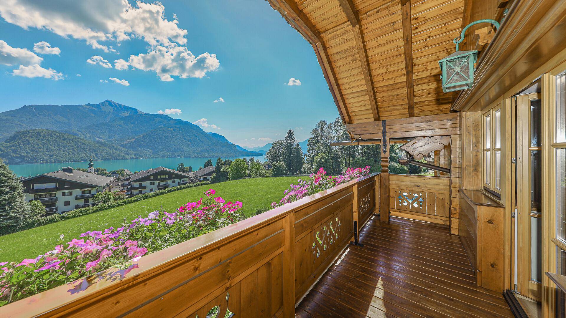 Traditioneller Holzbalkon mit Blumenkästen und atemberaubendem Blick auf den See und die Berge.
