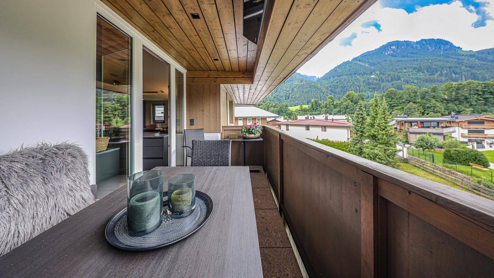 Sonniger Balkon mit Esstisch und Stühlen, ideal für Mahlzeiten im Freien mit Bergblick.