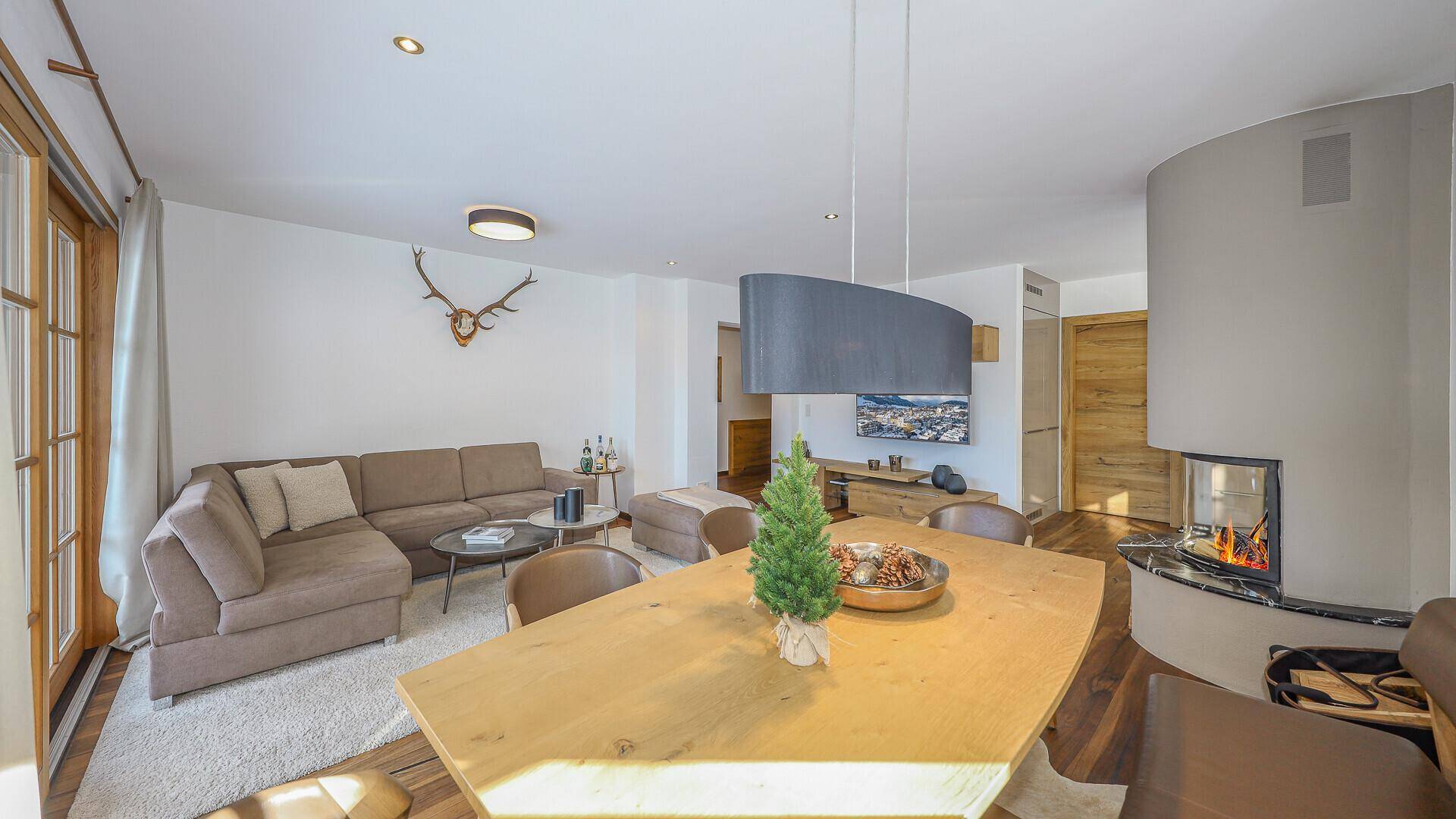 Einladender Wohn-Essbereich mit Kamin, bequemer Couch und Blick ins Grüne.