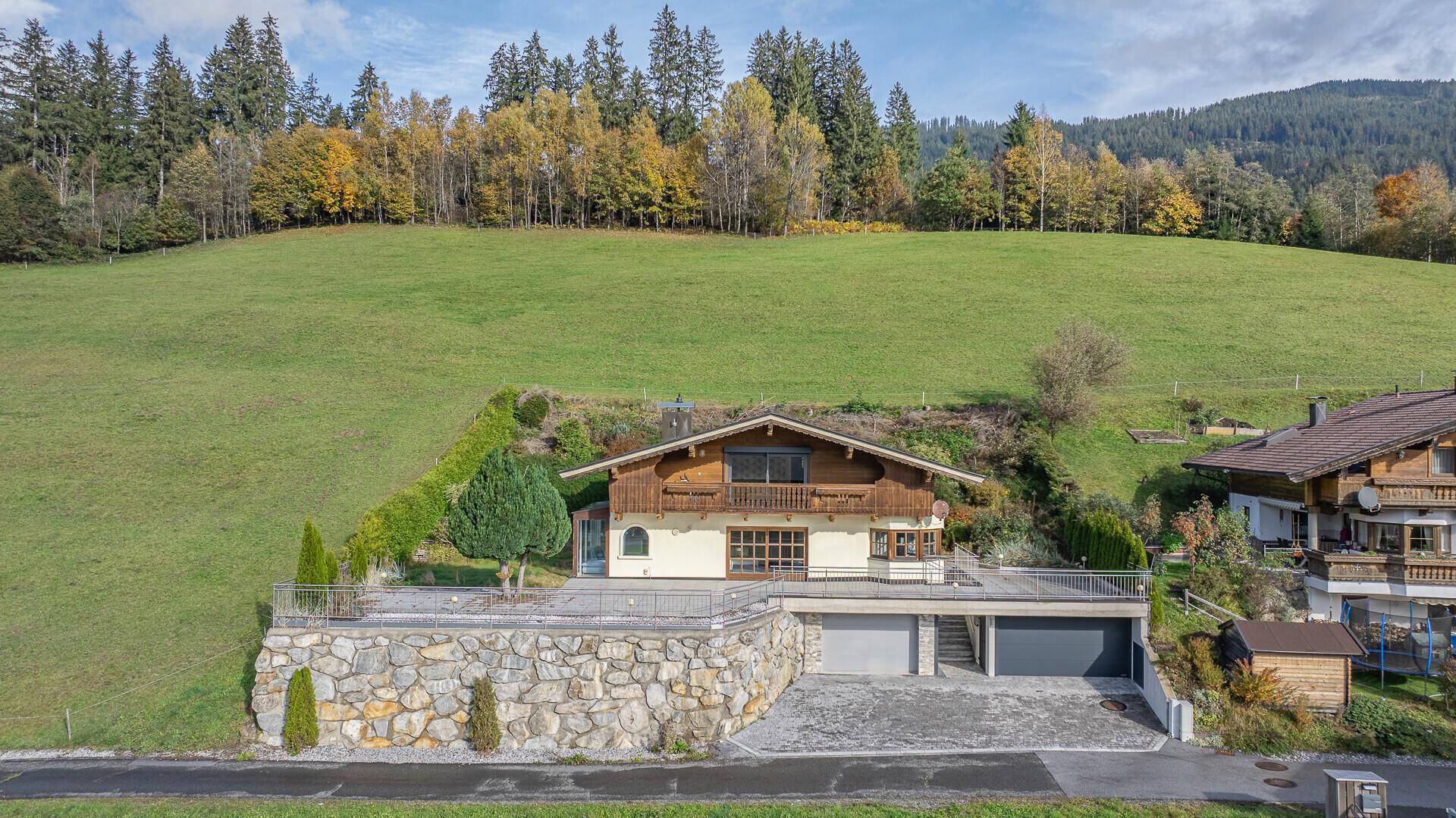 Ansicht des Hauses mit traditioneller Holzverkleidung, Steinfundament und zwei Garagentoren.