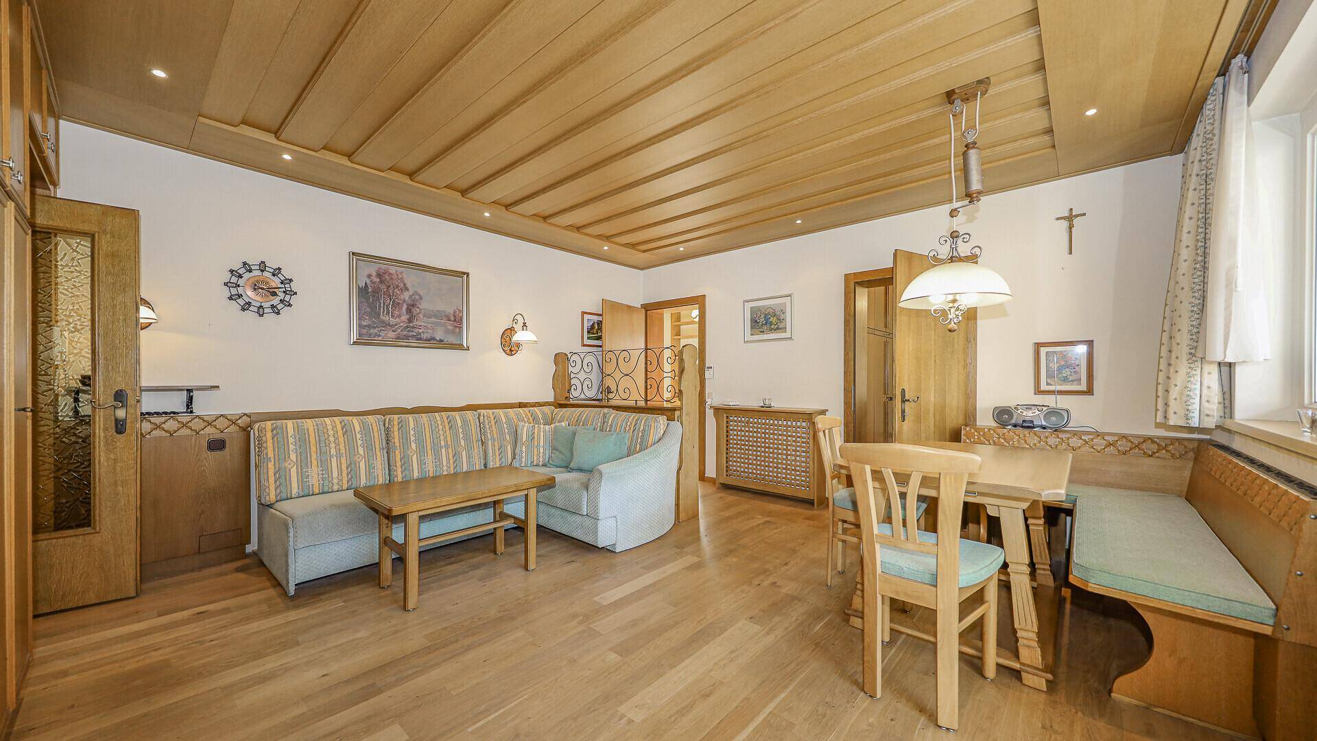 Traditionelles Wohn-Esszimmer mit Holzdecke, gestreiftem Sofa und rustikalem Essbereich.