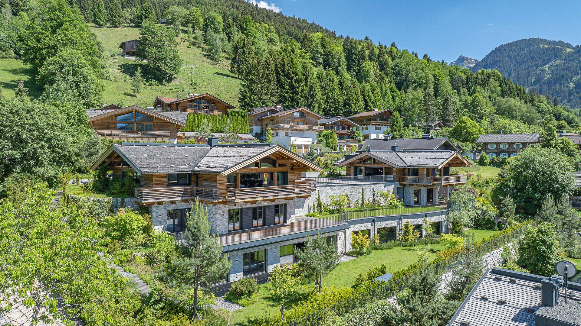Moderne Chalets harmonisch in die grüne Berglandschaft integriert, mit weitem Blick auf die Natur.