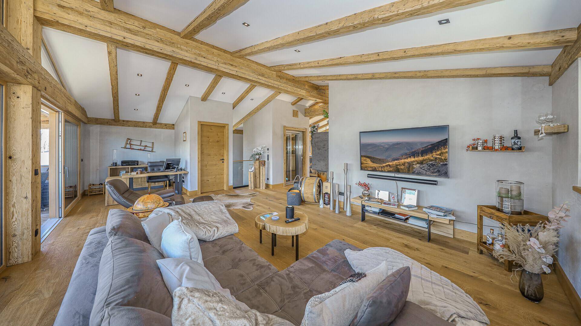 Geräumiges Wohnzimmer mit bequemer Couch, Holzbalken und modernem Interieur.