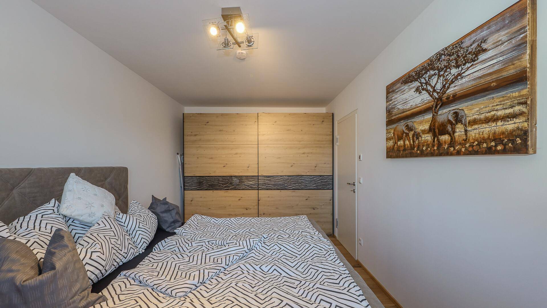 Gemütliches Schlafzimmer mit bequemen Bett und großem Holzschrank.