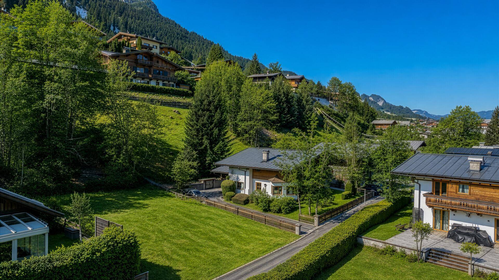 Charmantes Haus mit gepflegtem Garten und Blick auf die umliegenden bewaldeten Berge.