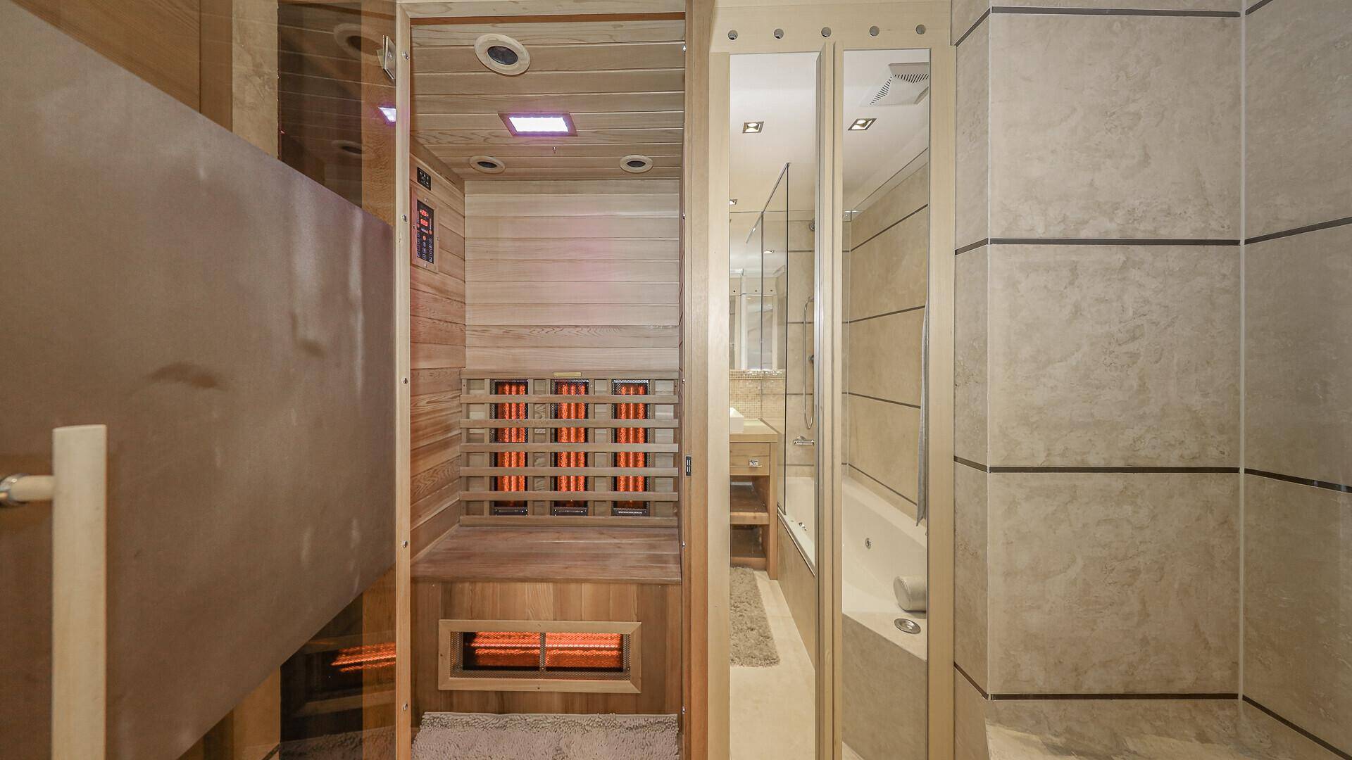 Wellnessbereich mit moderner Infrarotsauna und angrenzendem Badezimmer mit Badewanne.