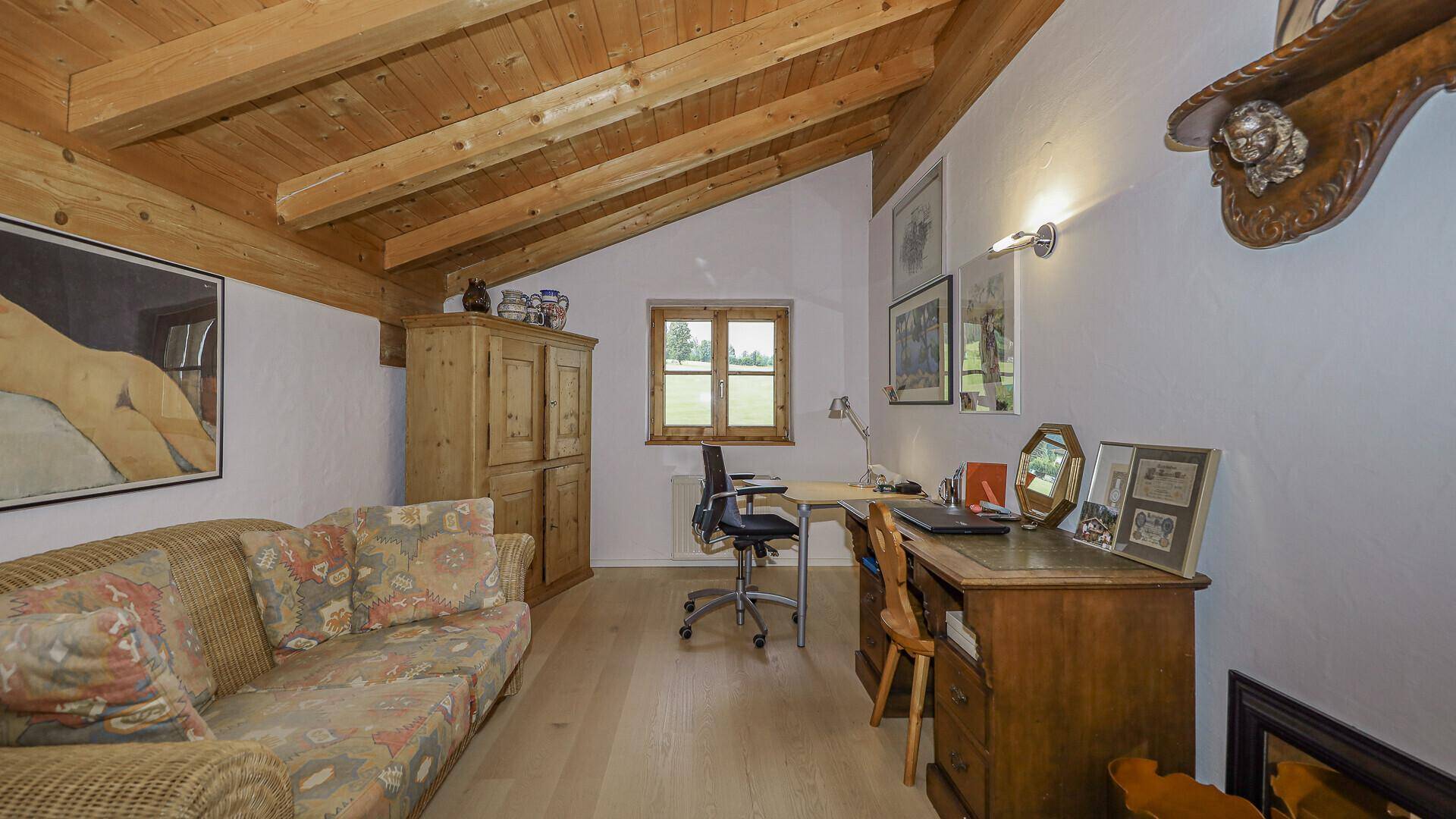 Arbeitszimmer im Dachgeschoss mit Holzbalkendecke, Holzboden und Blick ins Grüne.