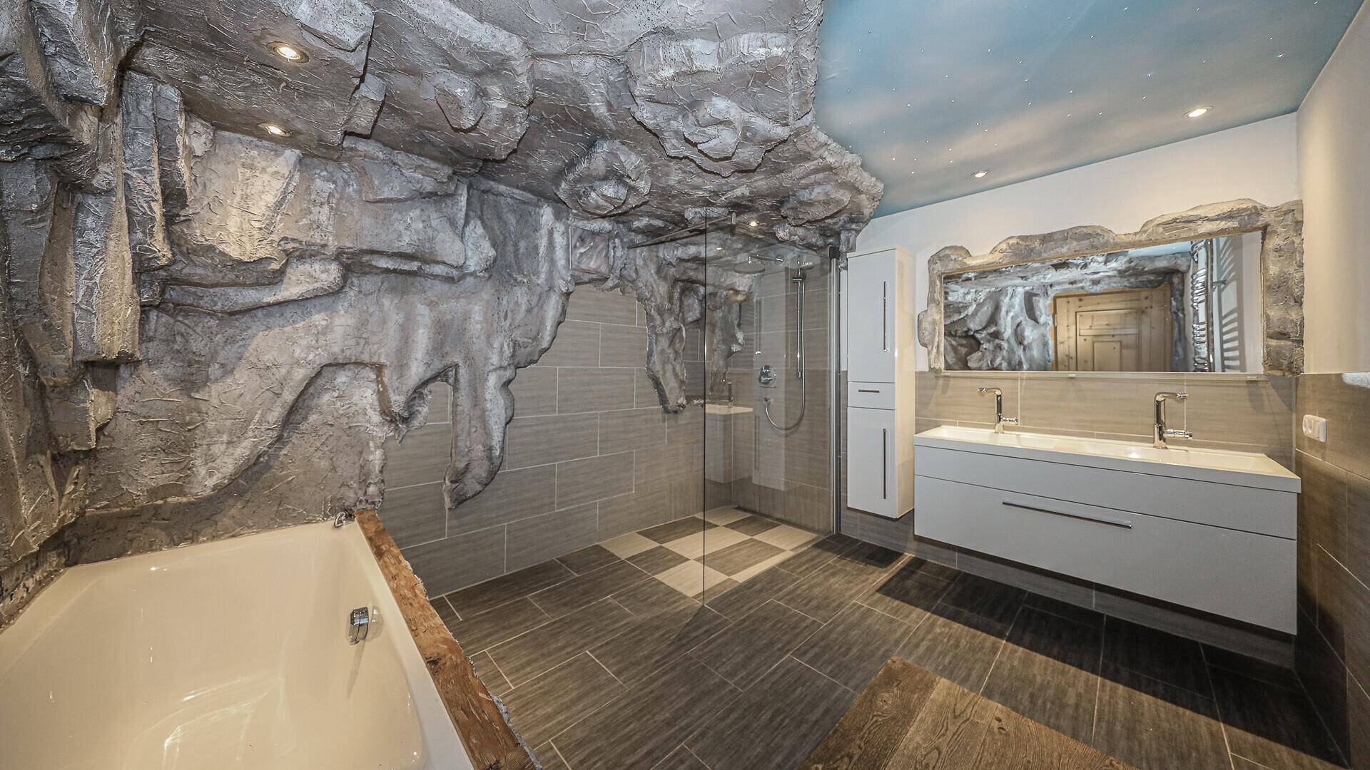 Außergewöhnliches Badezimmer mit Felsendesign, Badewanne, Dusche und Doppelwaschbecken.