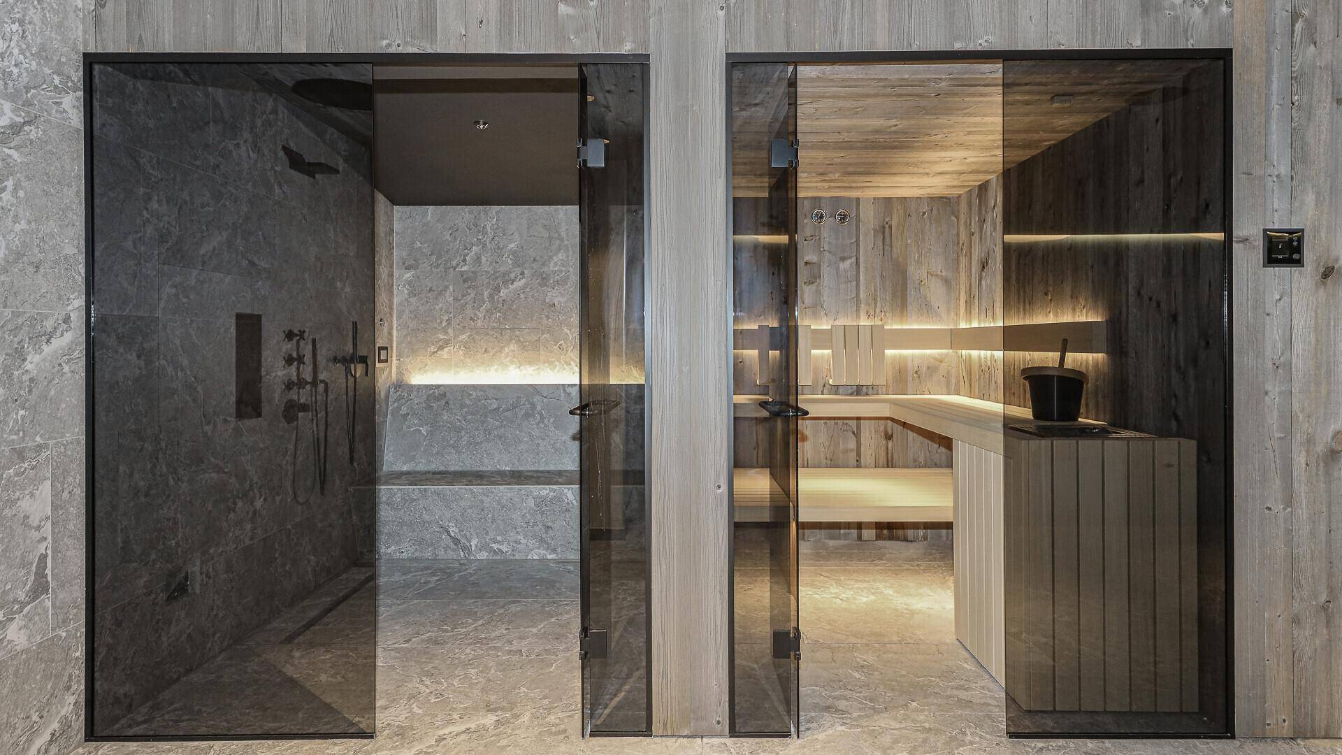 Exklusiver Wellnessbereich mit Dampfbad und Sauna, getrennt durch elegante Glaswände.