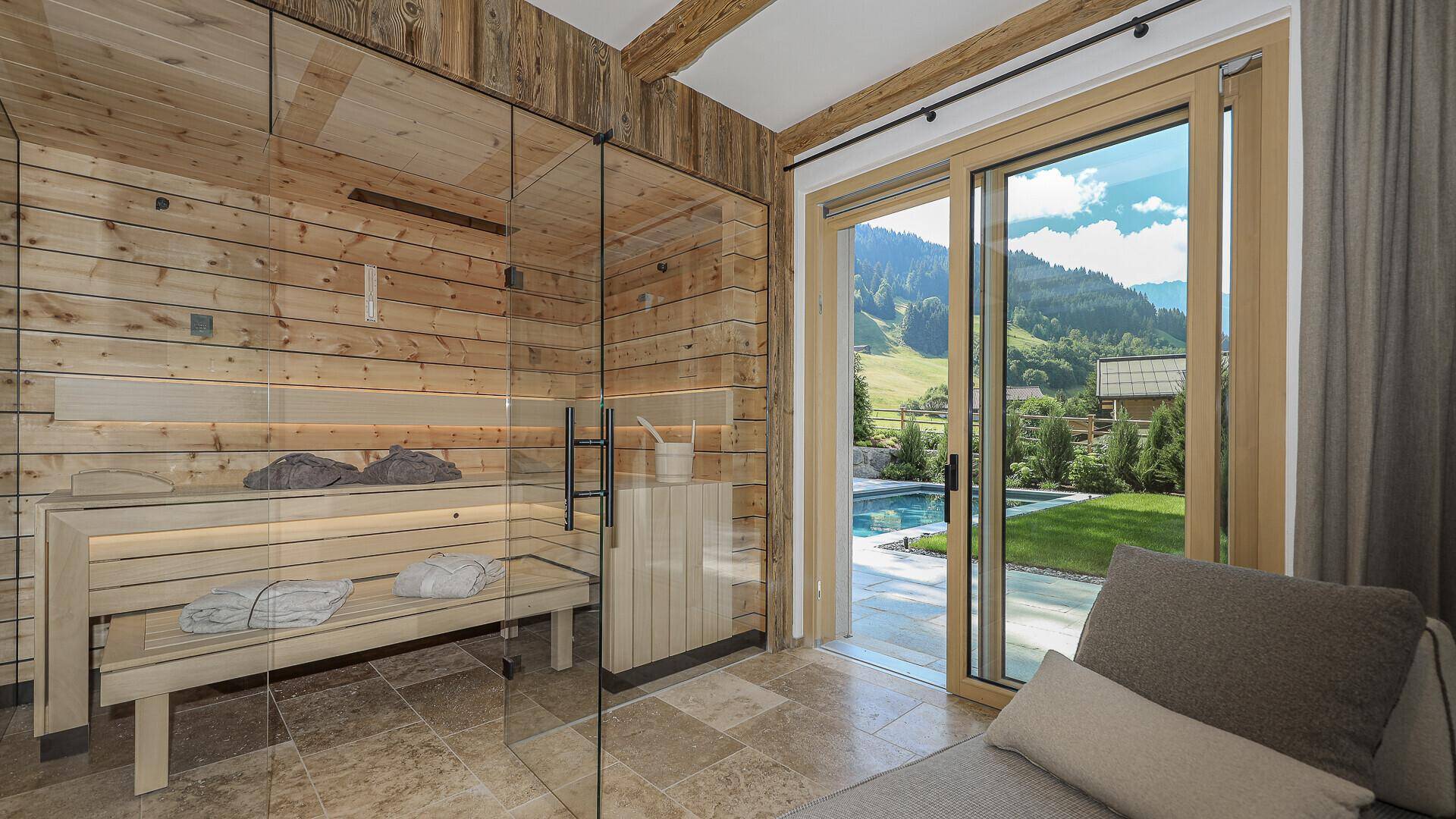Sauna mit Glasfront und Liegefläche, mit direktem Zugang zum Außenbereich und Pool.
