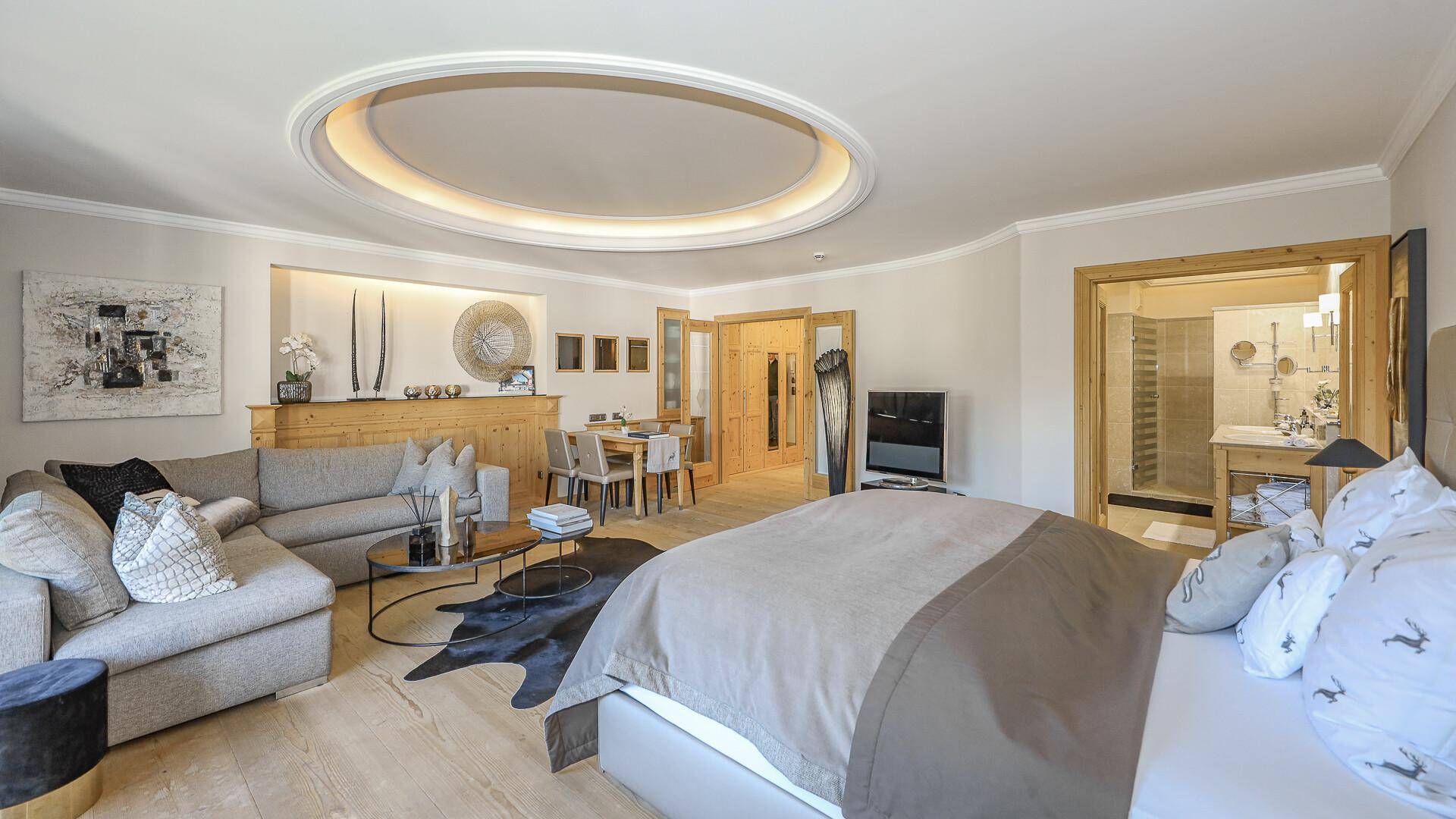 Großzügiger Wohn- und Schlafbereich mit Holzelementen, Parkettboden und Blick ins Badezimmer.
