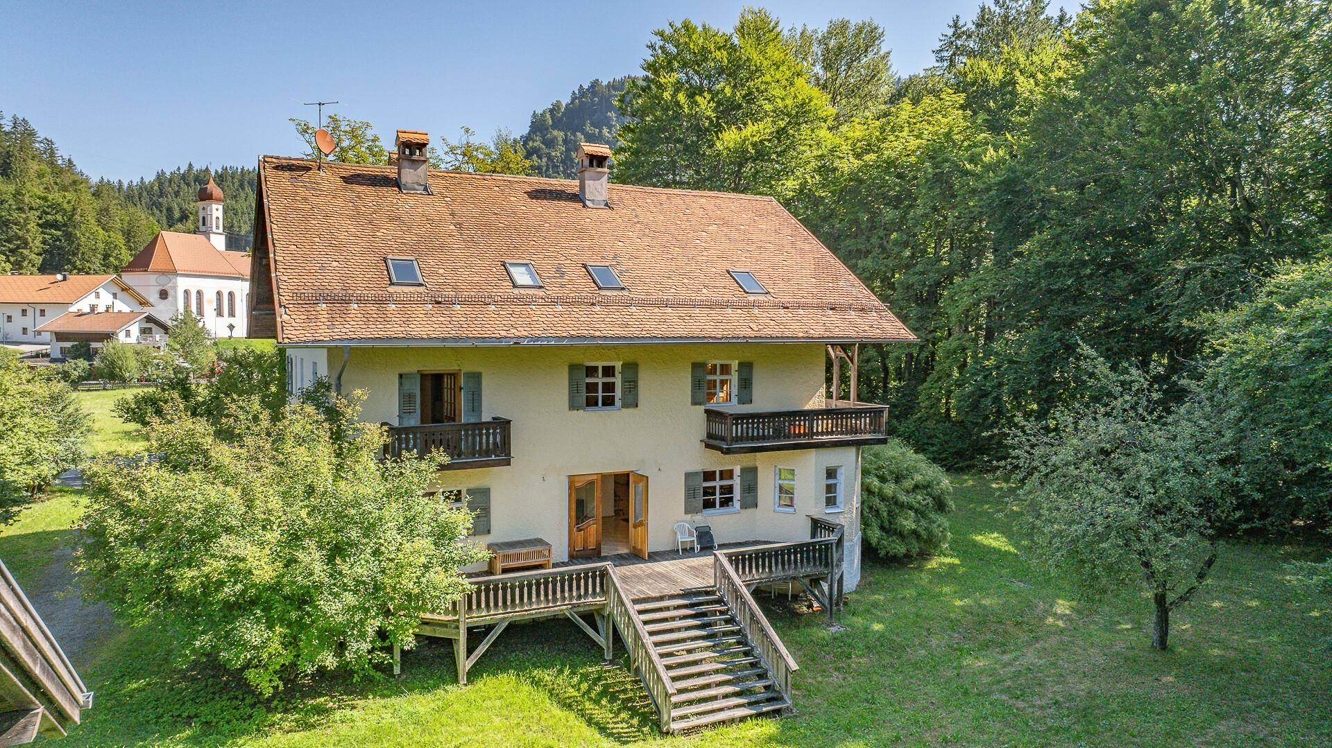 Luftaufnahme des Hauses mit Satteldach, umgeben von Wald und mit Blick auf die Hügellandschaft.