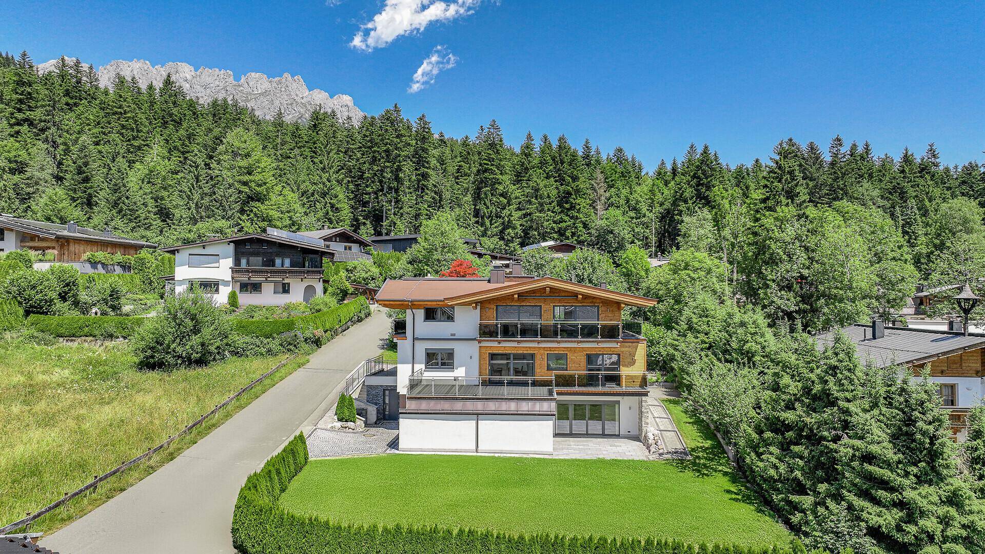 Modernes Wohnhaus in den Alpen mit Holzakzenten und weitläufigem Garten.