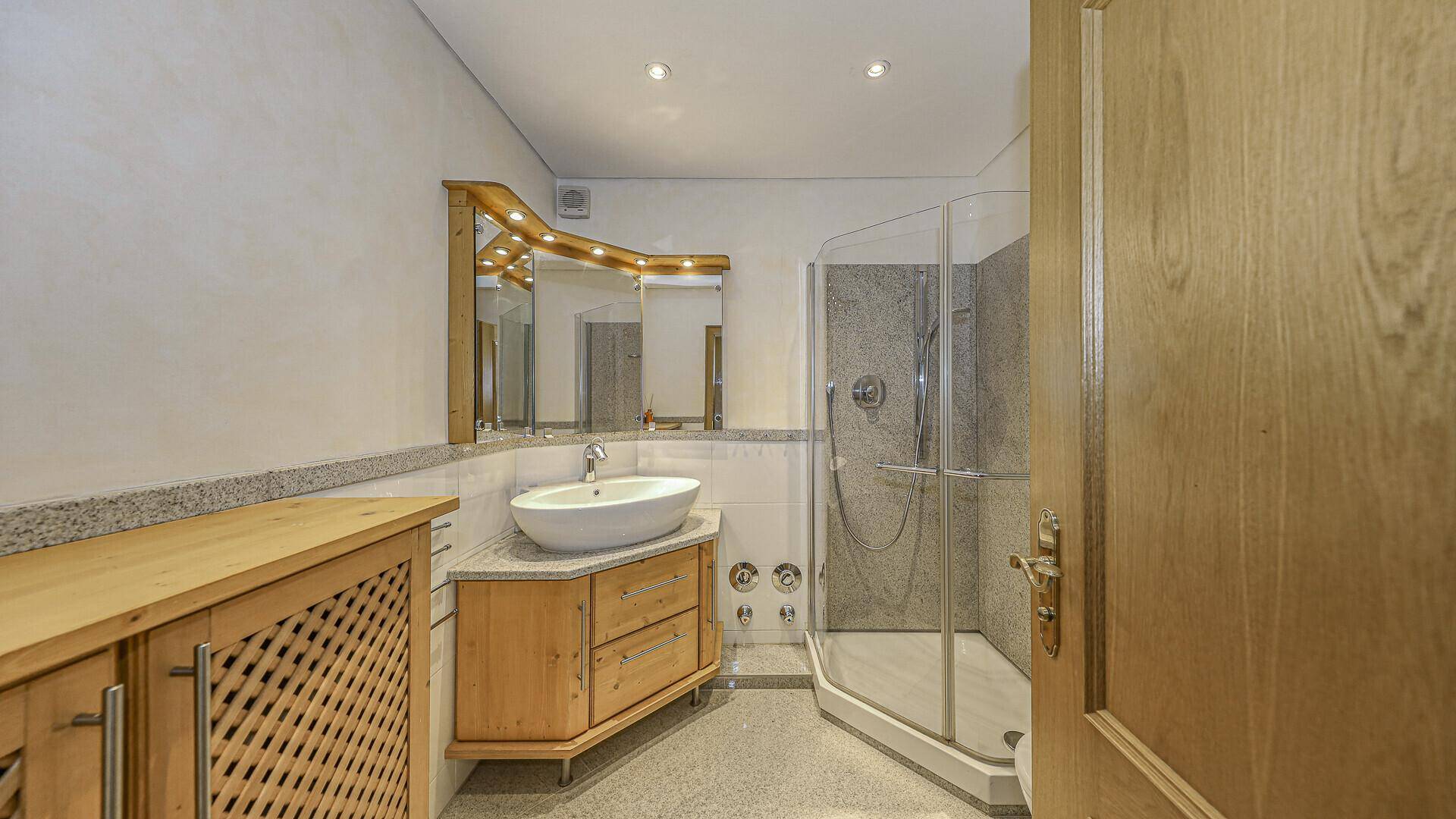 Helles Badezimmer mit Waschtisch, Spiegelschrank und Duschkabine.