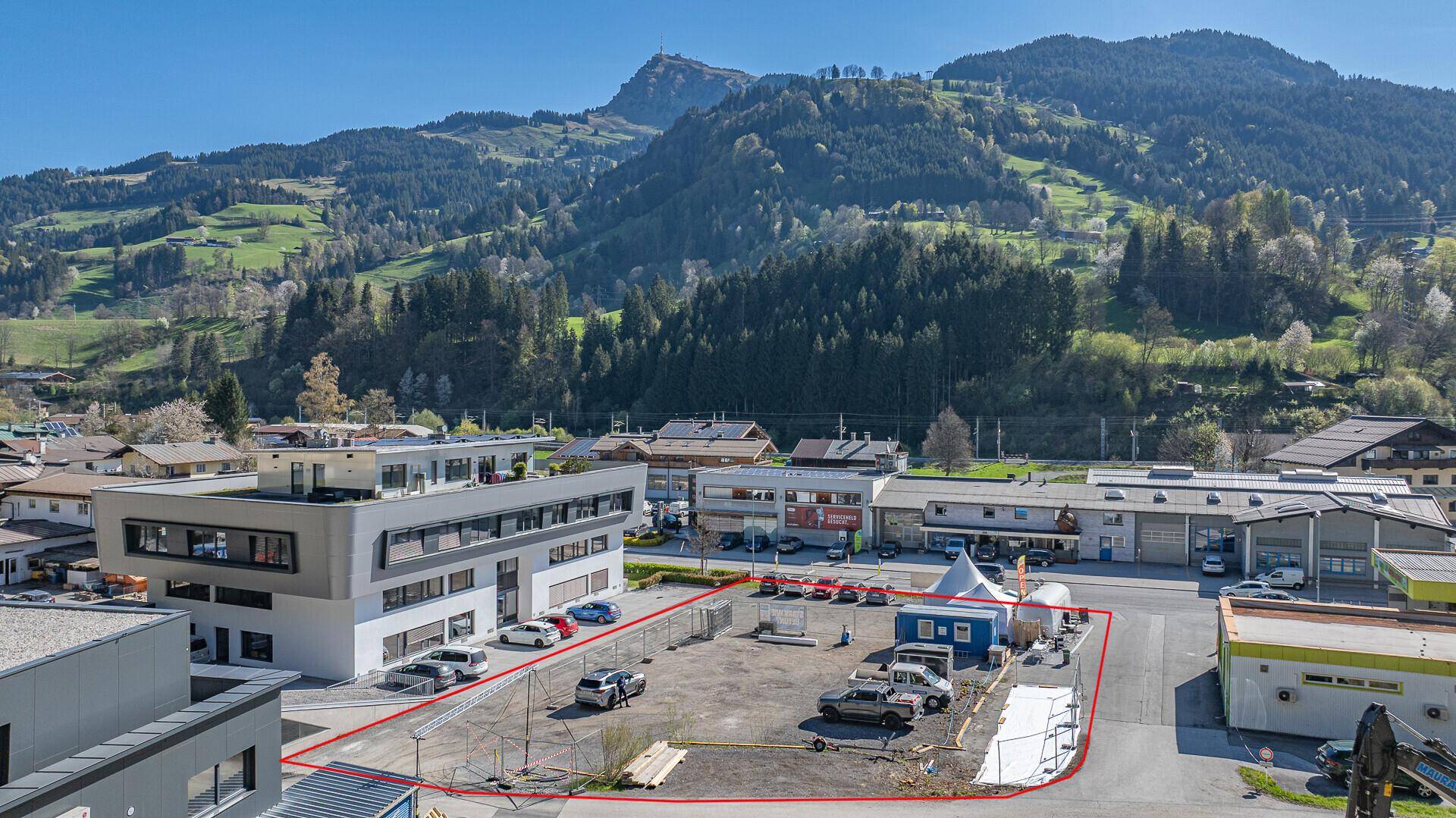 Detaillierte Luftansicht des Grundstücks mit modernen Gebäuden und einer Baustelle am Hang.