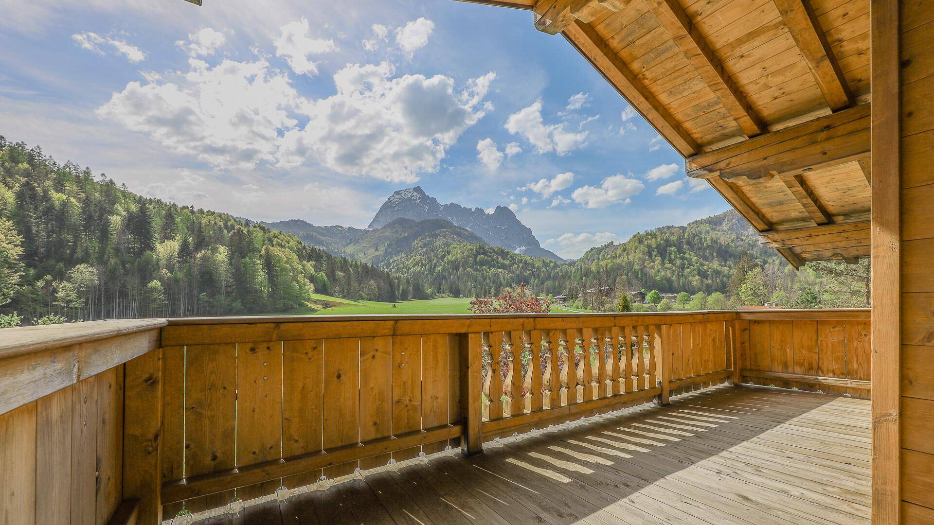 Holzbalkon mit traditionellem Geländer und Panoramablick auf die umliegende Bergwelt.