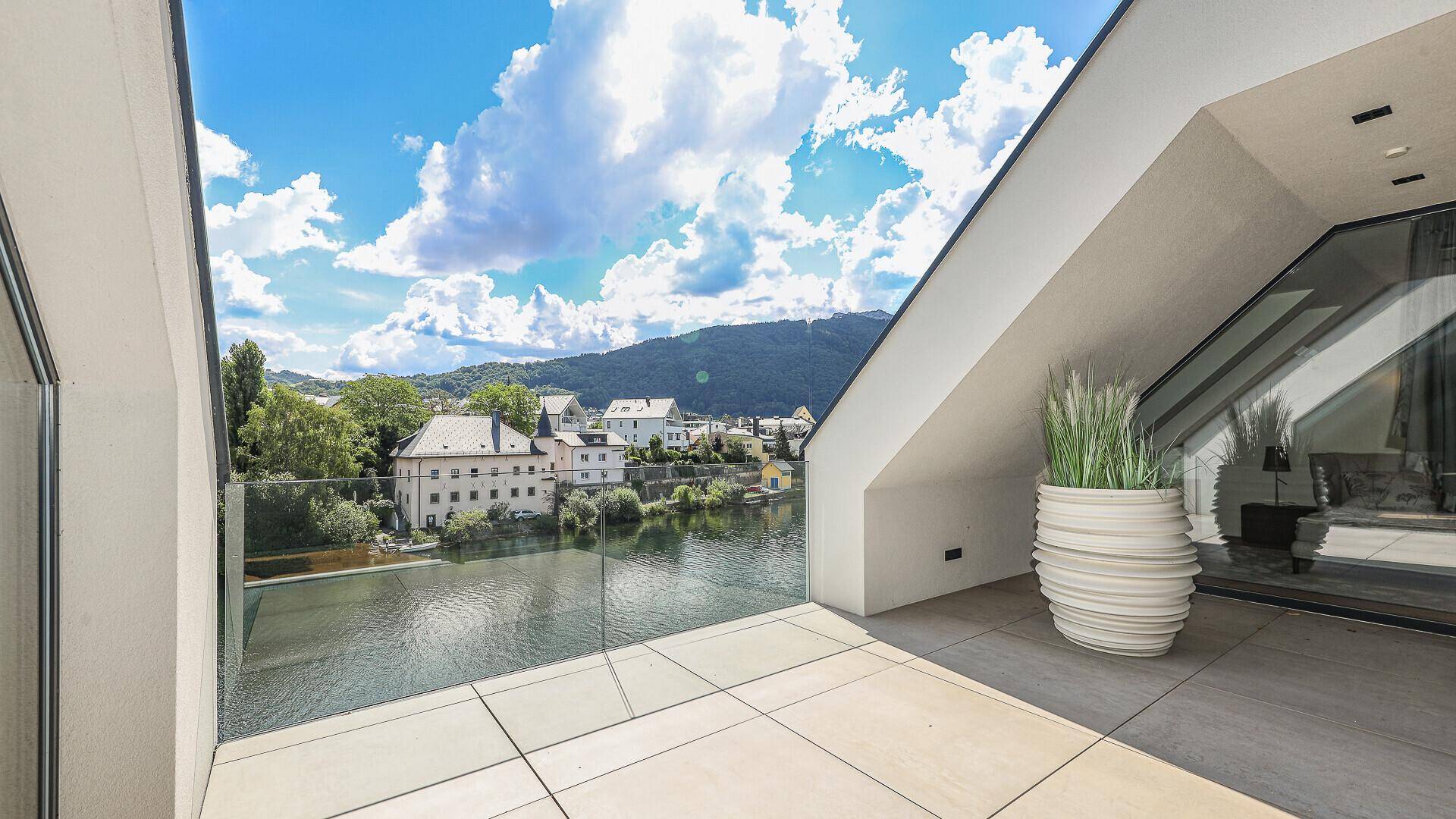 Geräumige Terrasse mit Glasgeländer und atemberaubendem Blick auf den See und die Stadt.