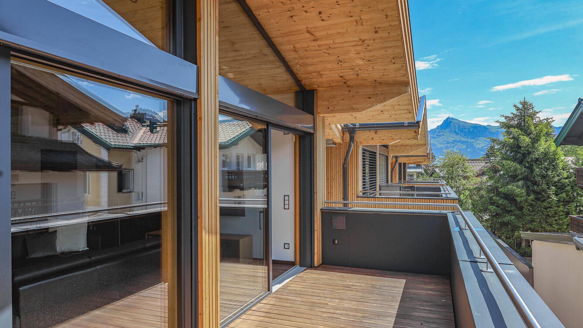 Heller Balkon mit Holzboden und Zugang zum Innenbereich, bietet einen weiten Bergblick.