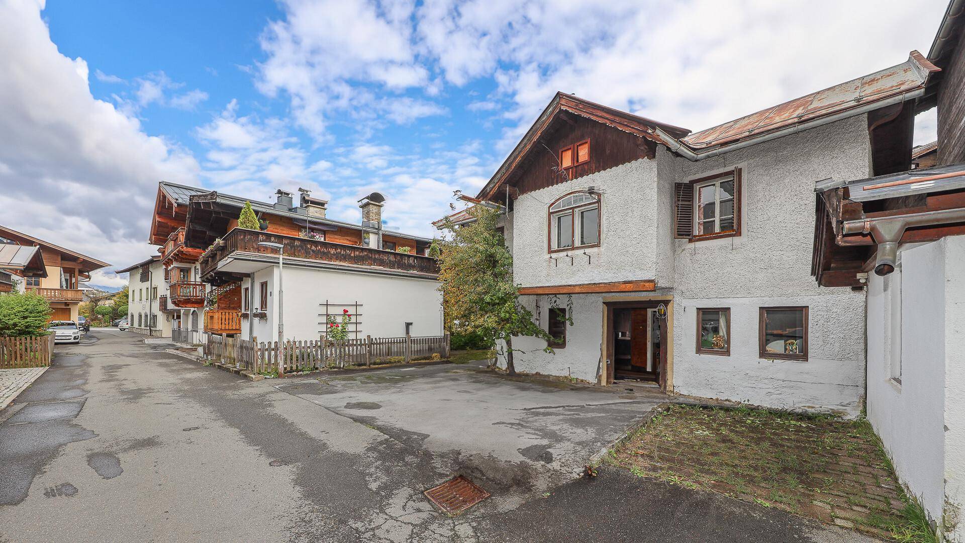 Ansicht eines älteren Hauses mit Putzfassade und Holzelementen von der Straße aus.