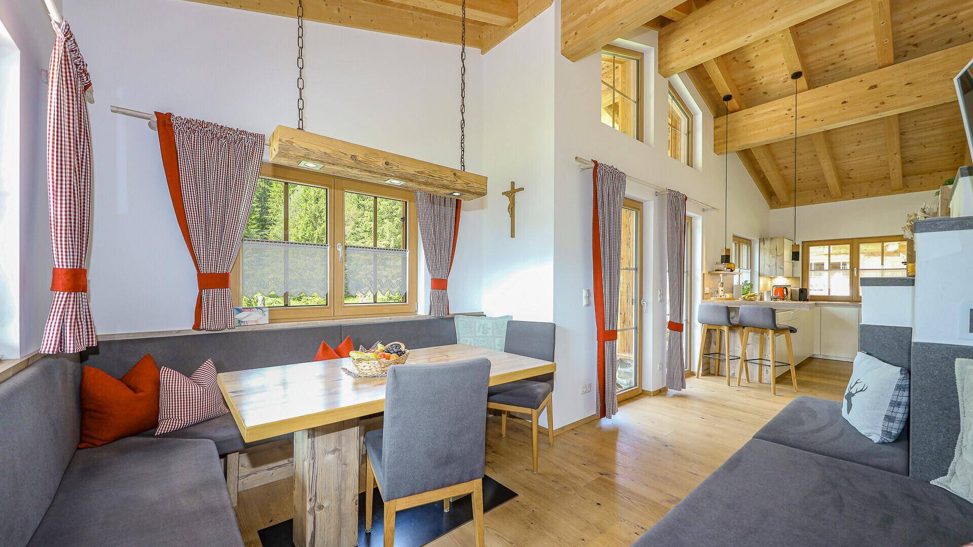 Heller Wohn- und Essbereich im alpinen Stil mit Holzbalkendecke, gemütlicher Sitzecke und offener Küche.