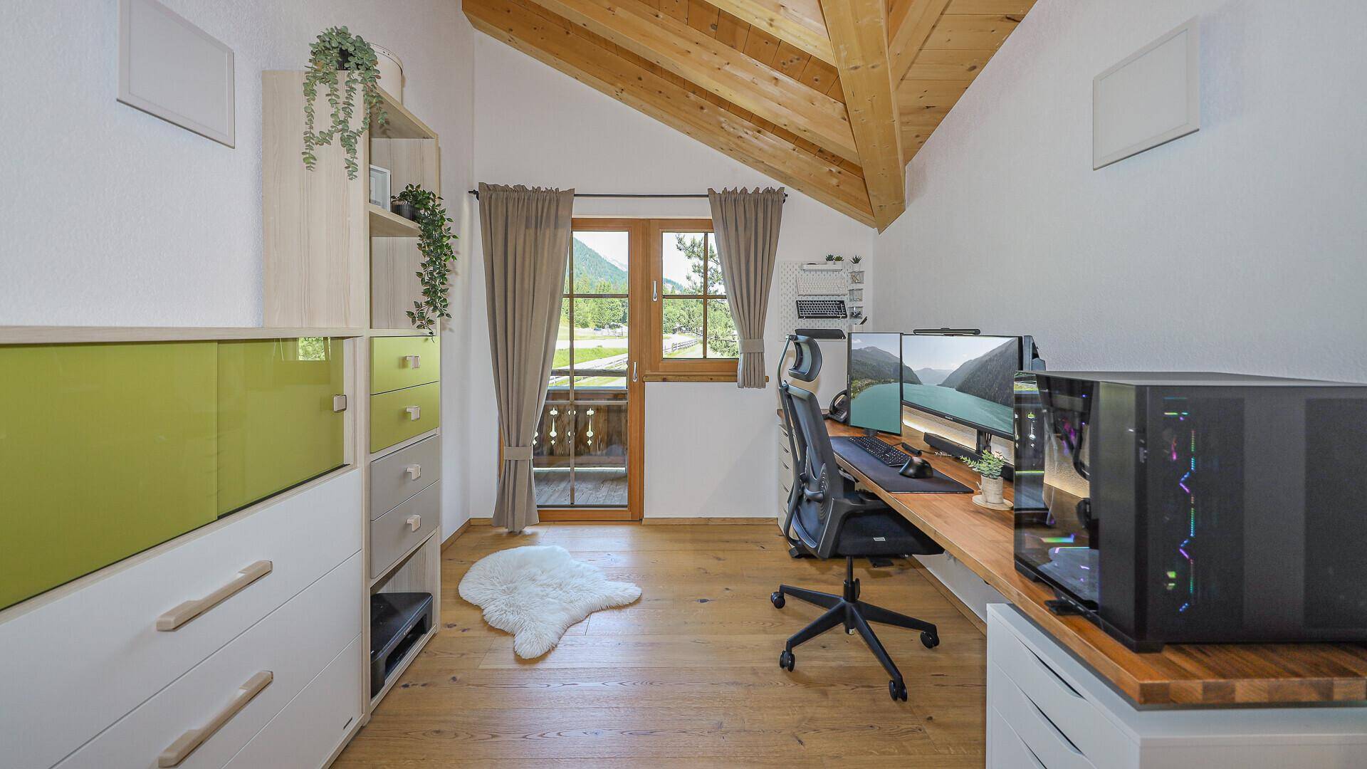 Modernes Arbeitszimmer mit Holzdachschrägen, Schreibtisch und Blick auf die umliegende Natur.
