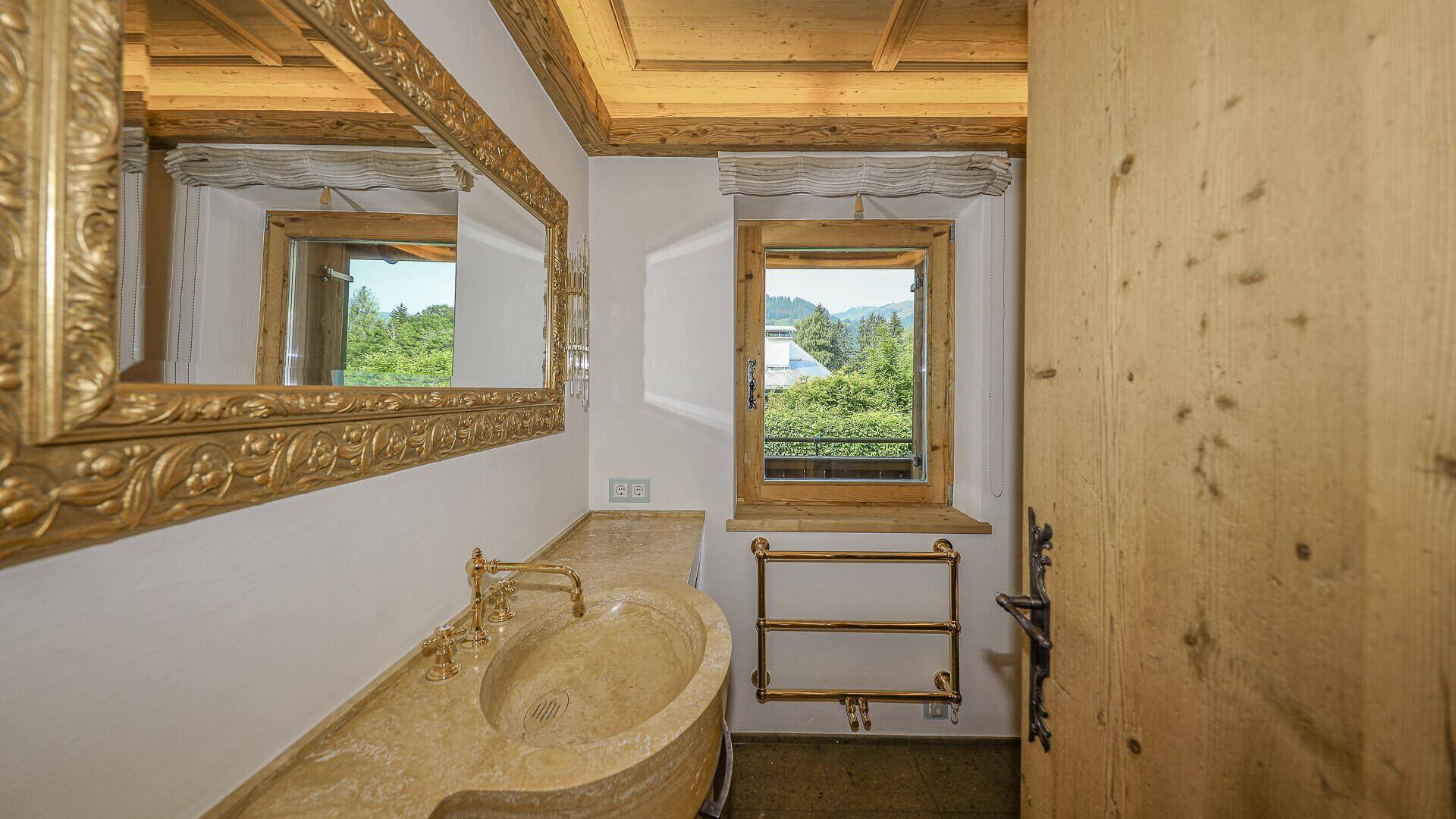Badezimmer mit Steinwaschbecken, großem Spiegel und Fenster mit Bergblick.