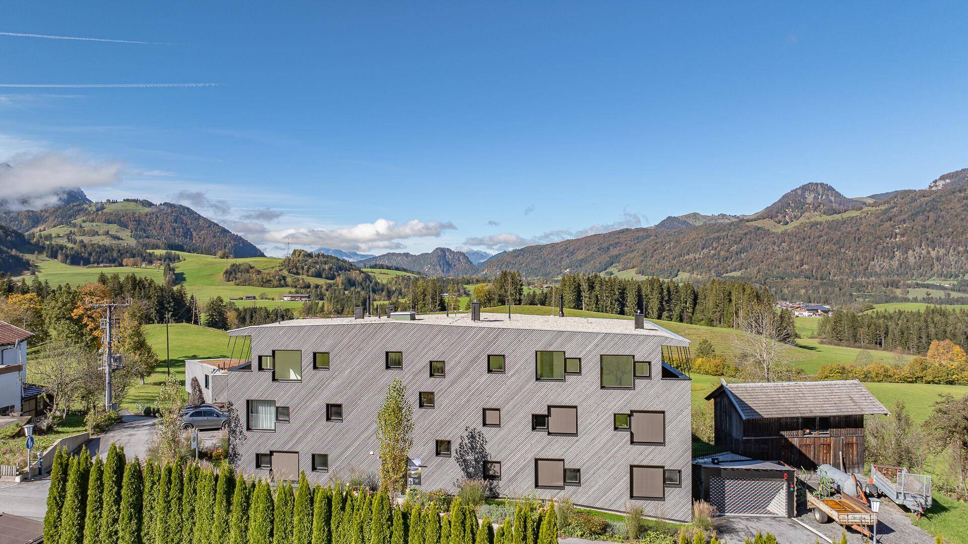 Einzigartige Fassade des modernen Gebäudes mit unregelmäßig angeordneten Fenstern und Bergblick.