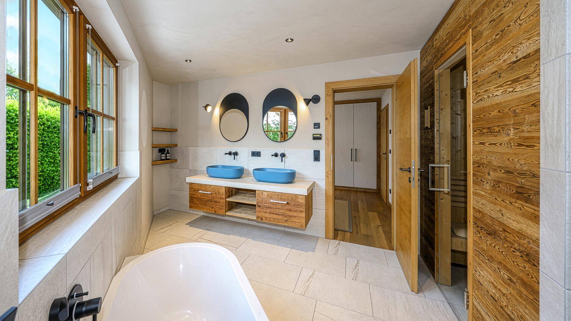 Elegantes Badezimmer mit Doppelwaschbecken, Badewanne und Sauna, hell und modern gestaltet.