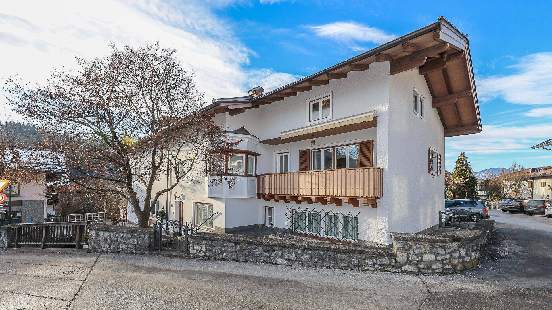 Traditionelles Gebäude mit Holzbalkon und Erker, umgeben von einer winterlichen Dorflandschaft.