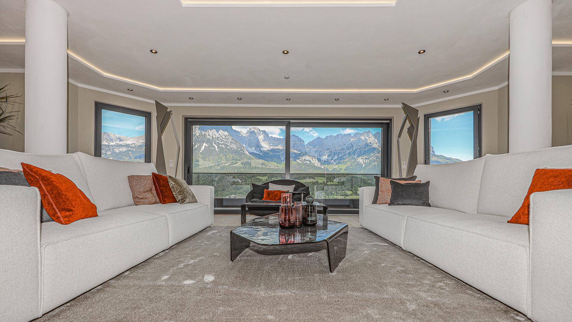 Gemütlicher Wohnbereich mit bequemen Sofas und atemberaubendem Panoramablick auf die Berge.