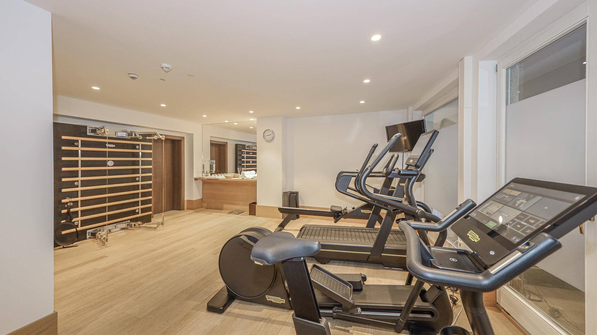 Gut ausgestatteter Fitnessraum mit modernen Trainingsgeräten und Spiegelflächen.