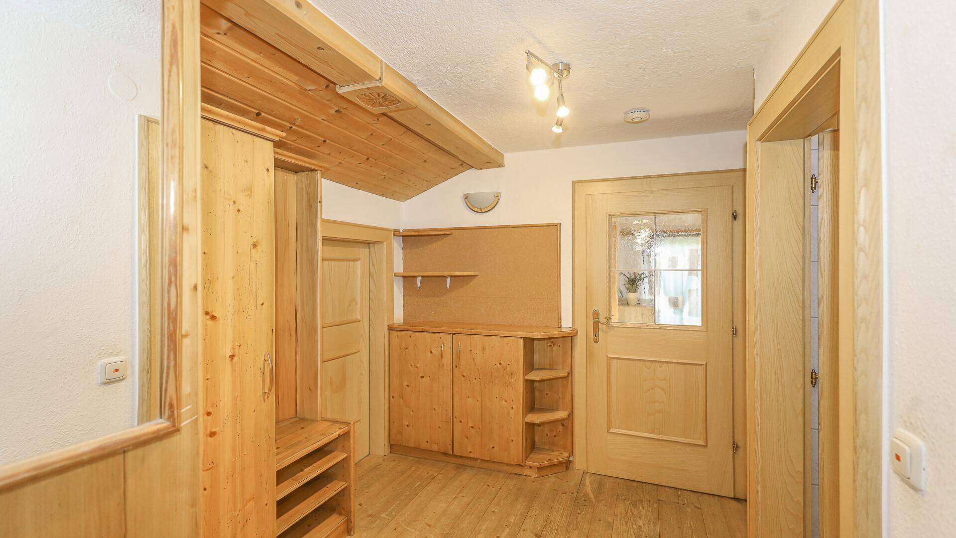 Heller Eingangsbereich mit Holzmöbeln und Garderobe, einladend und funktional.