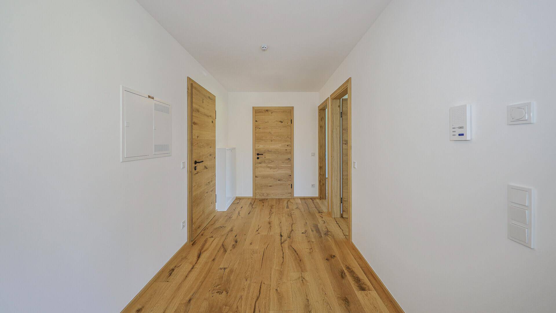 Heller Flur mit Holzboden und mehreren Holztüren, der zu verschiedenen Räumen führt.