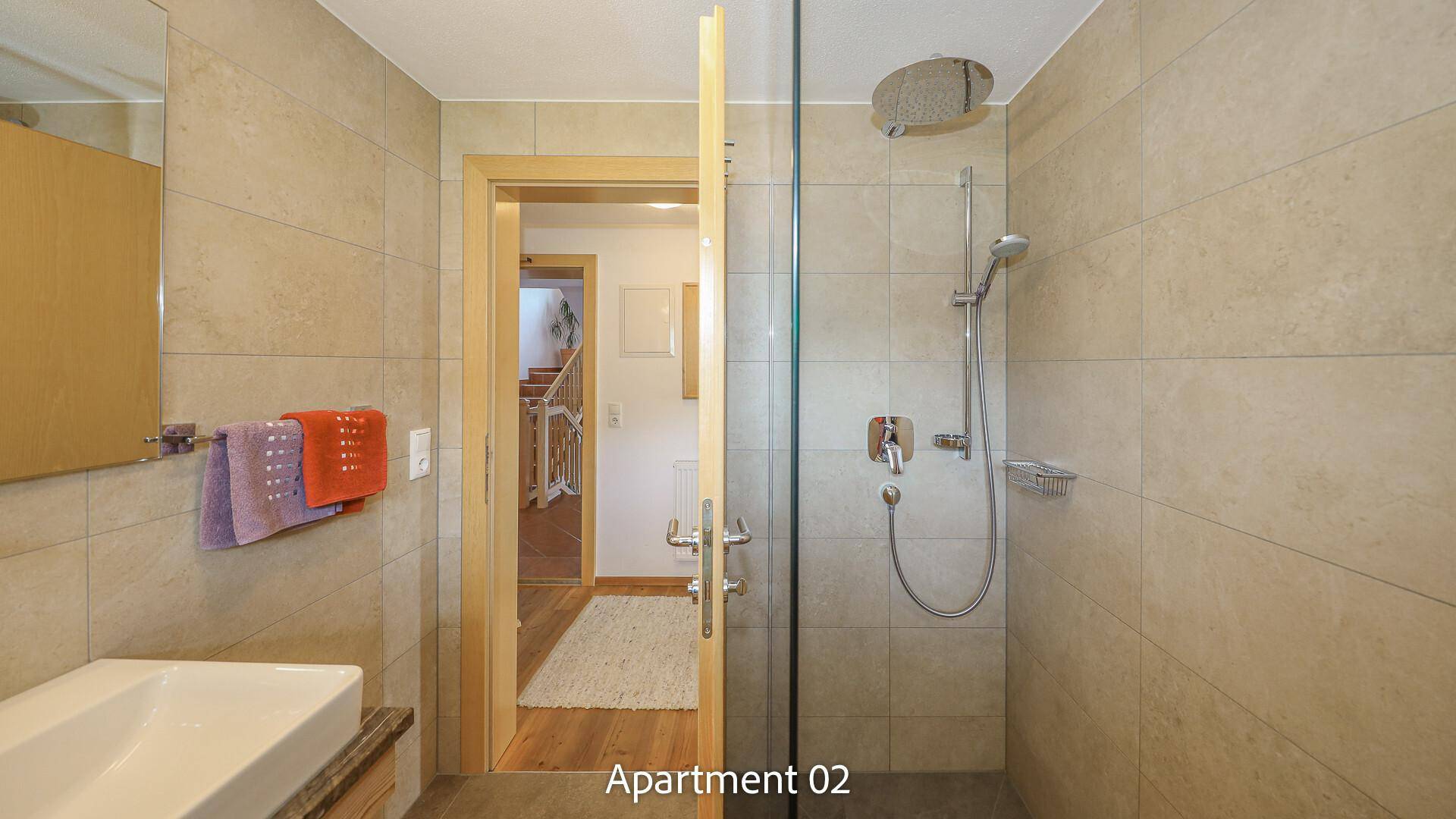 Modern geflieste Dusche mit Glasabtrennung und minimalistischem Waschbecken.